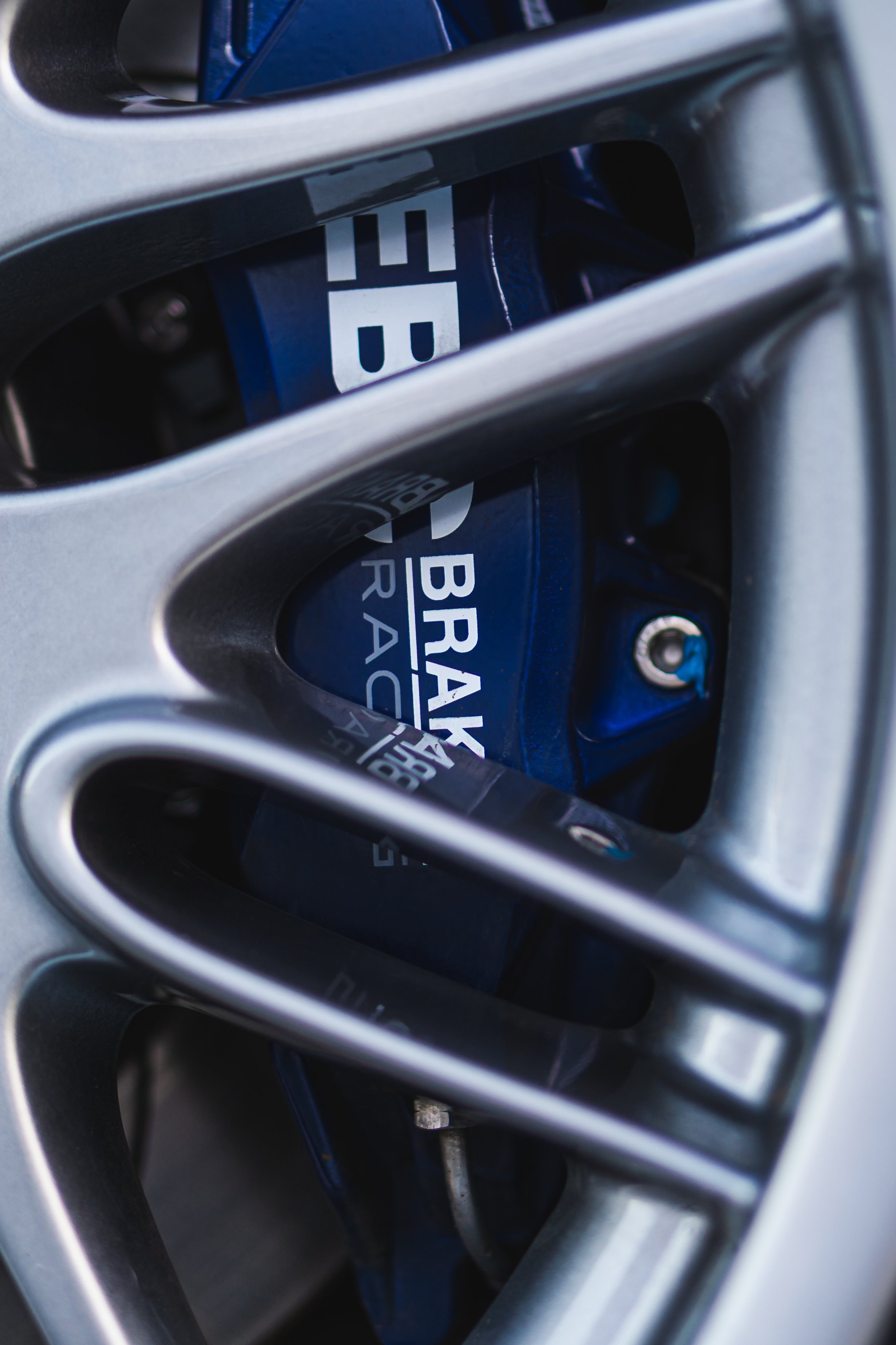 Close-up of a car's wheel with a brake rotor and red brake calipers visible through the spokes.