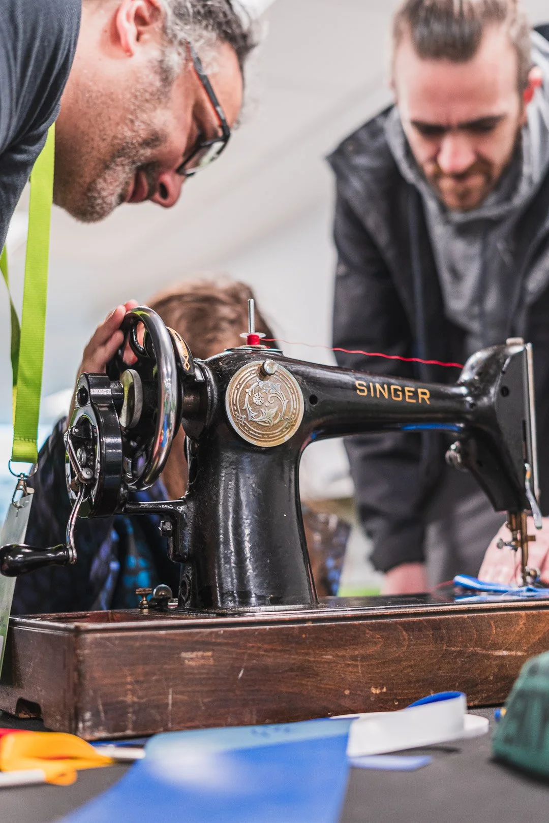 Two men working on a vintage Singer sewing machine.