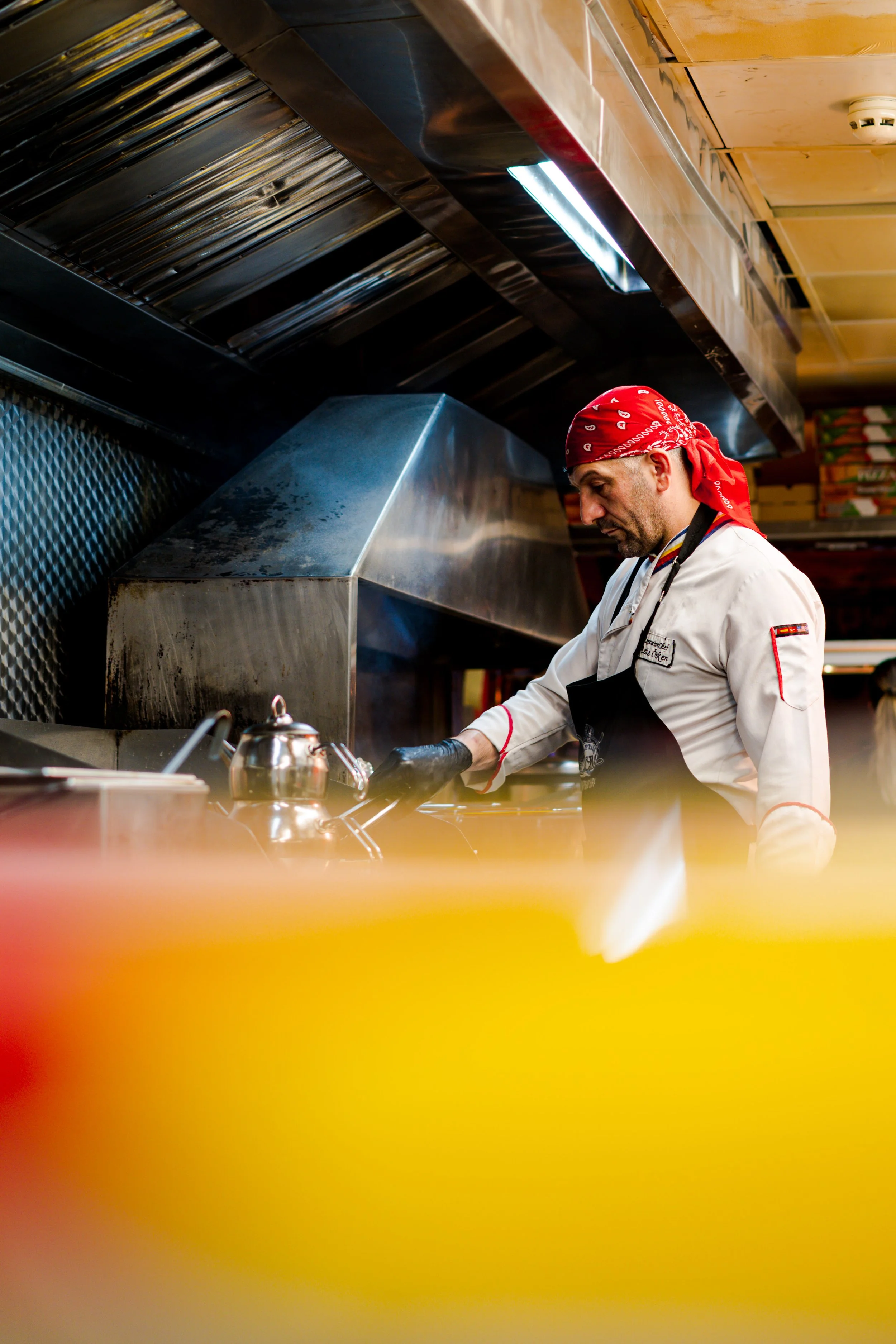 Chef in a white uniform and red bandana cooking in a commercial kitchen.