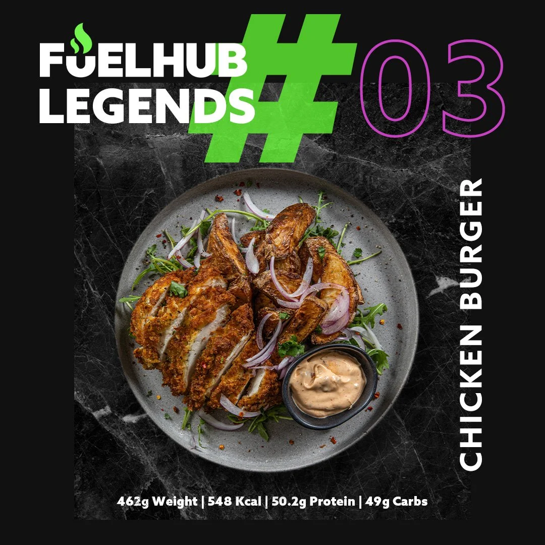 Plate of fried chicken tenders with onion slices, greens, and dipping sauce, on a black textured surface, with text overlay about Chicken Burger from Fuel Hub Legends.