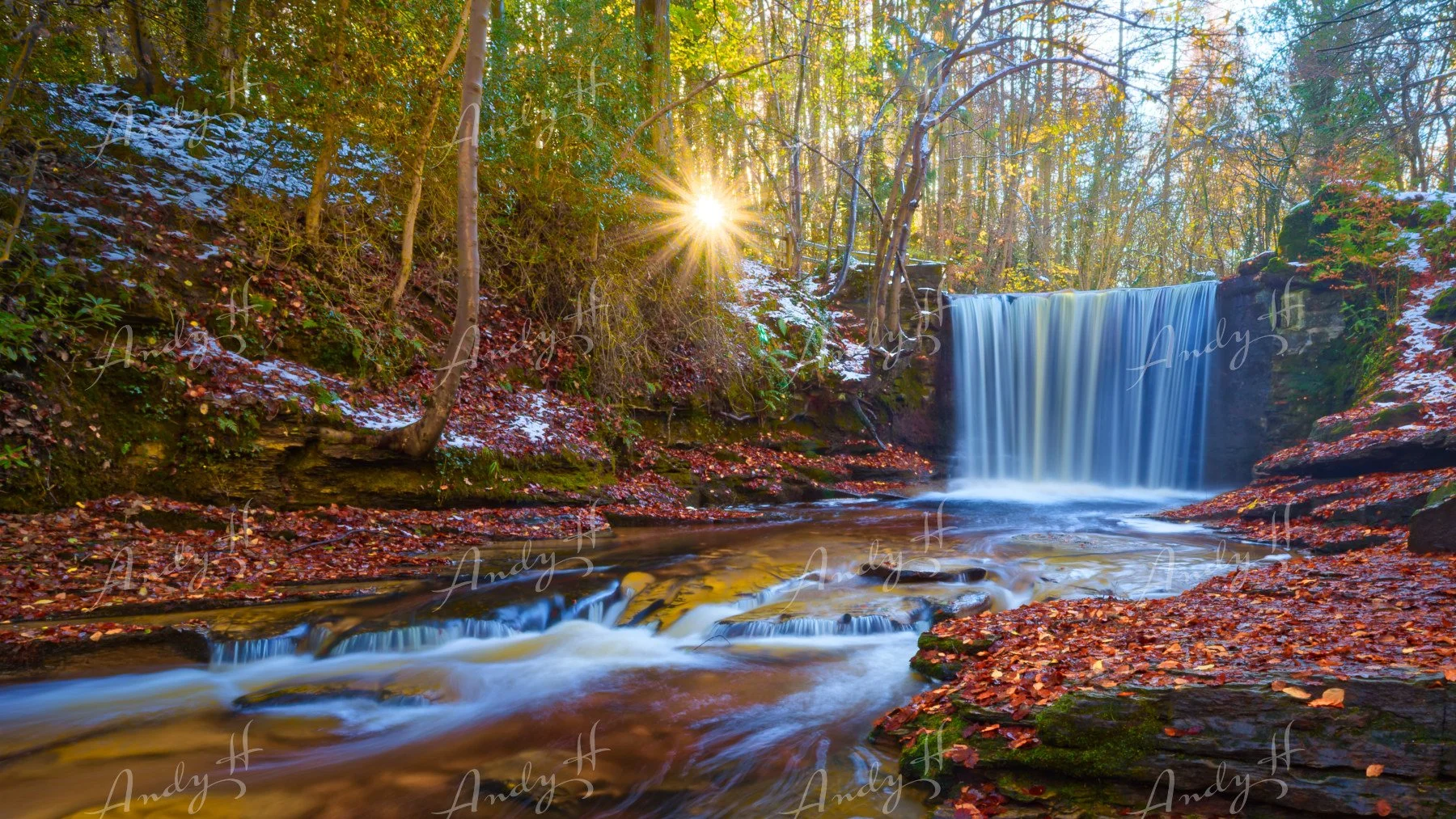Landscape Photography fine art print, A scenic waterfall with flowing water in a forest during fall, with a setting sun and some snow on the ground and the sun bursting through the trees, snowdonia