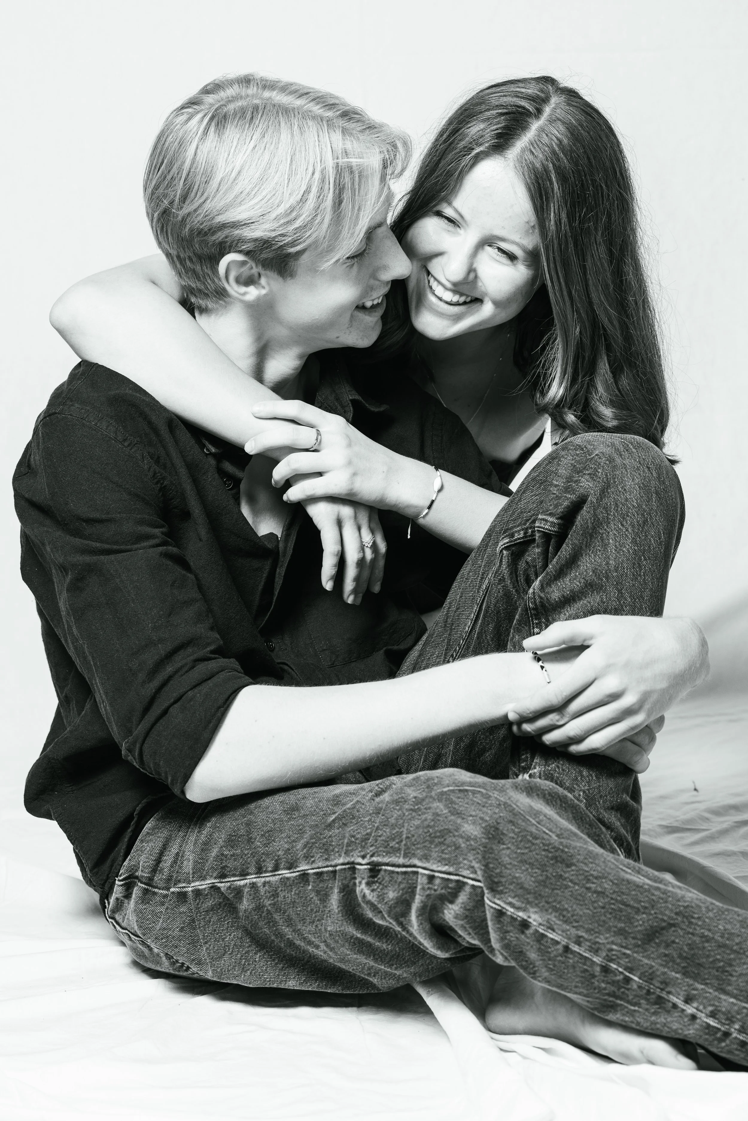A young man and woman in a black-and-white photo sharing a joyful moment, with the woman hugging the man and both smiling.