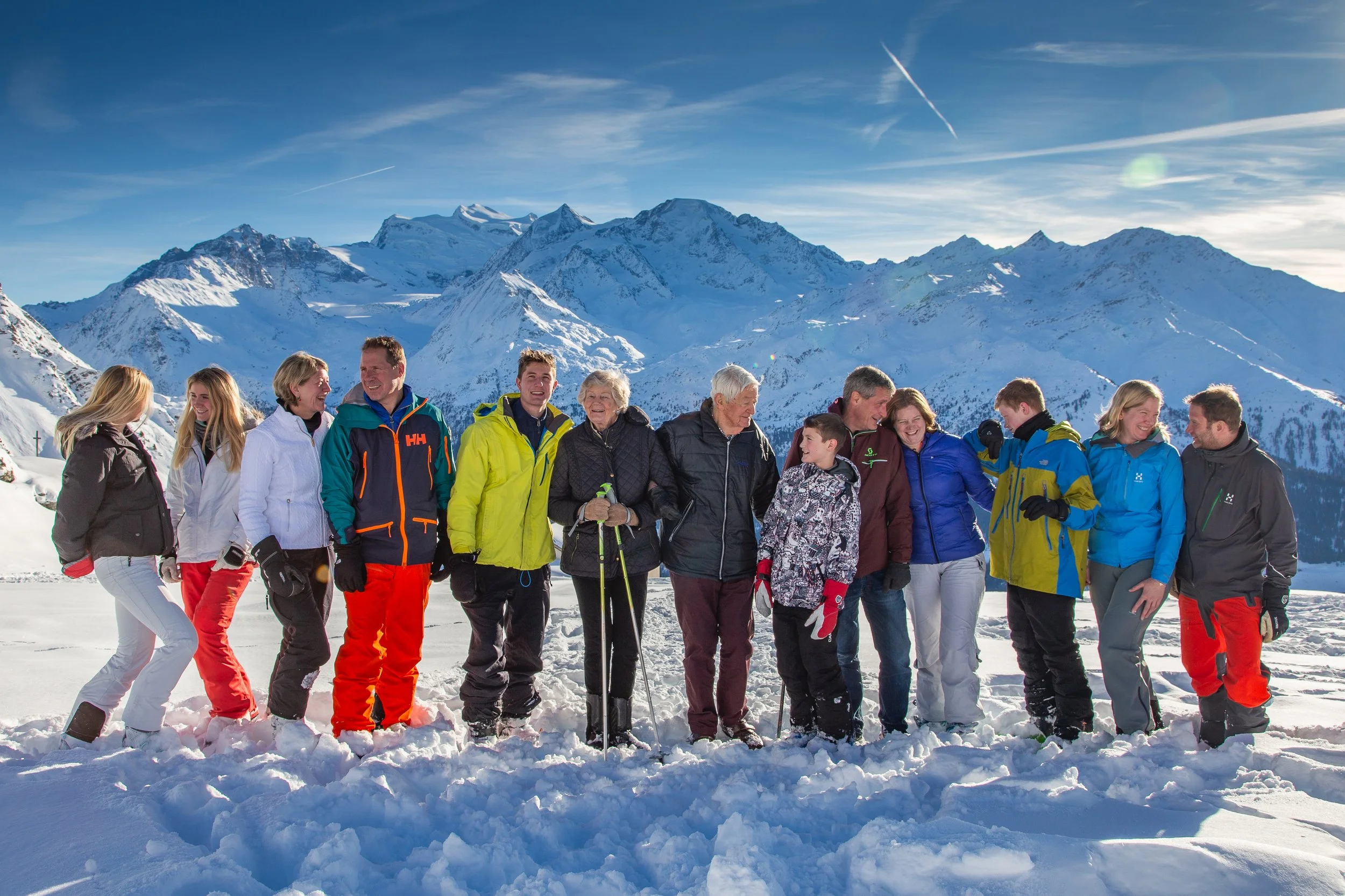 Group of people standing on snow in a mountainous winter landscape, smiling and enjoying a sunny day in Verbier Switzerland.