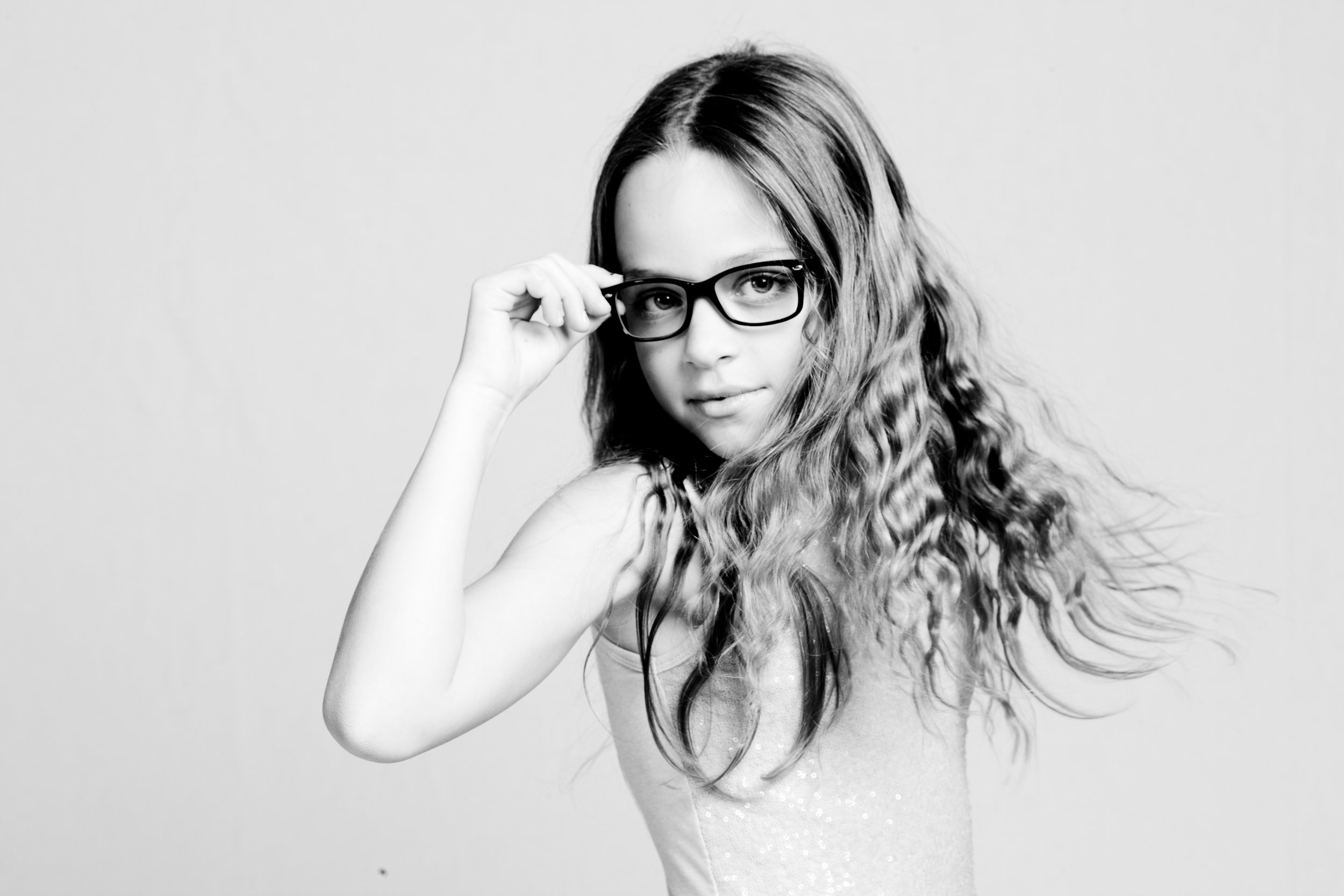 A young woman with long, wavy hair wearing glasses, looking at the camera with a slight smile.