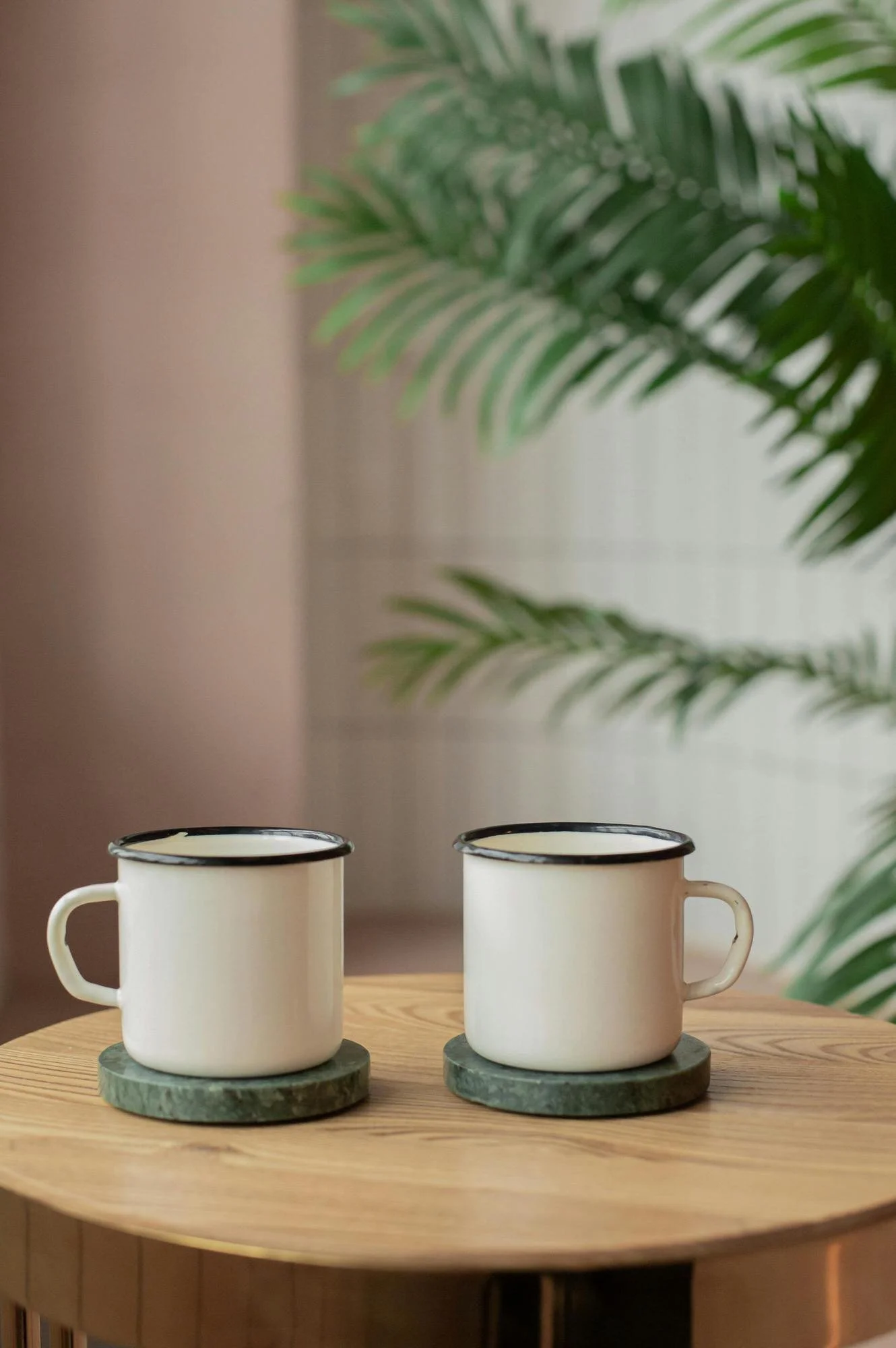 Attachment Therapy in NYC - 2 coffee mugs on green coasters atop a wooden table , plant in background