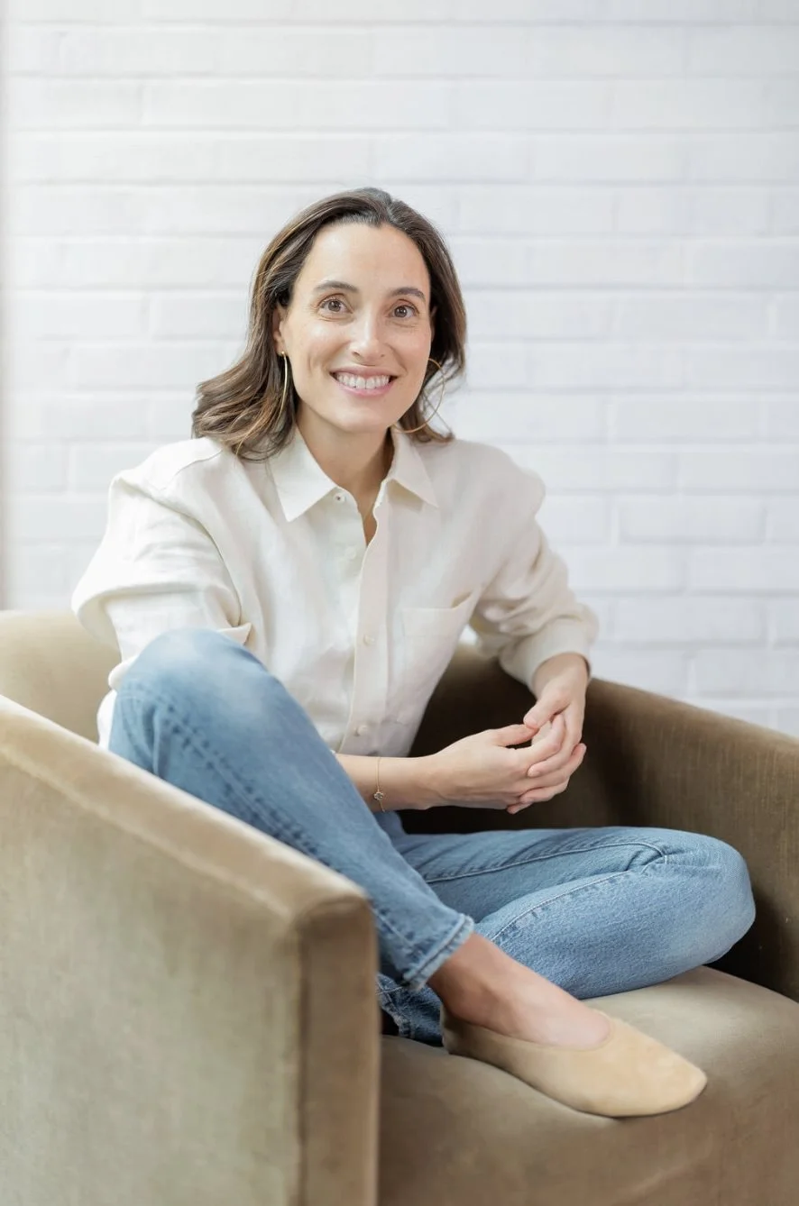 Alissa Friedlander, LCSW - in jeans and white shirt sitting on olive taupe colored chair