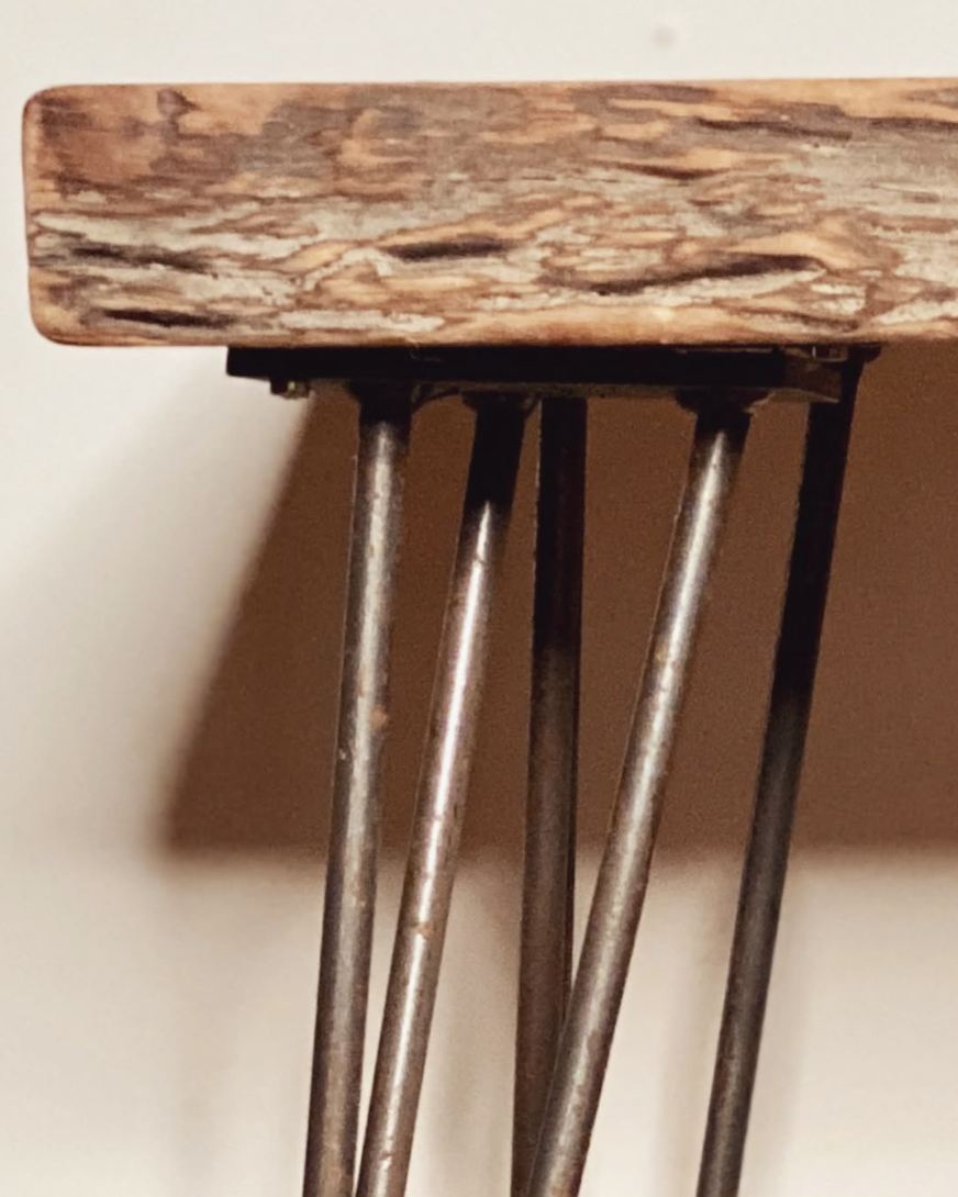 Close-up of a wooden table top with metal legs showing a modern furniture design.