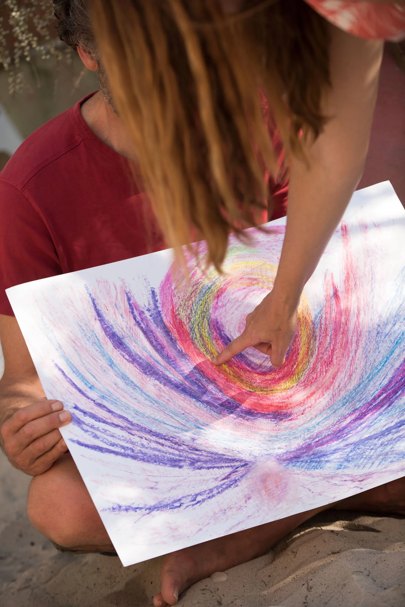 Deux personnes regardent une œuvre d'art abstraite colorée créée avec des pastels, représentant un tourbillon de couleurs, lors du stage La Sagesse des Vagues.