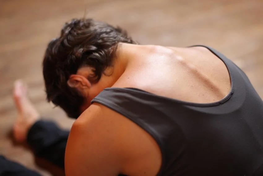 Femme étirant en mains et genoux, vue du dos, sur un sol en bois