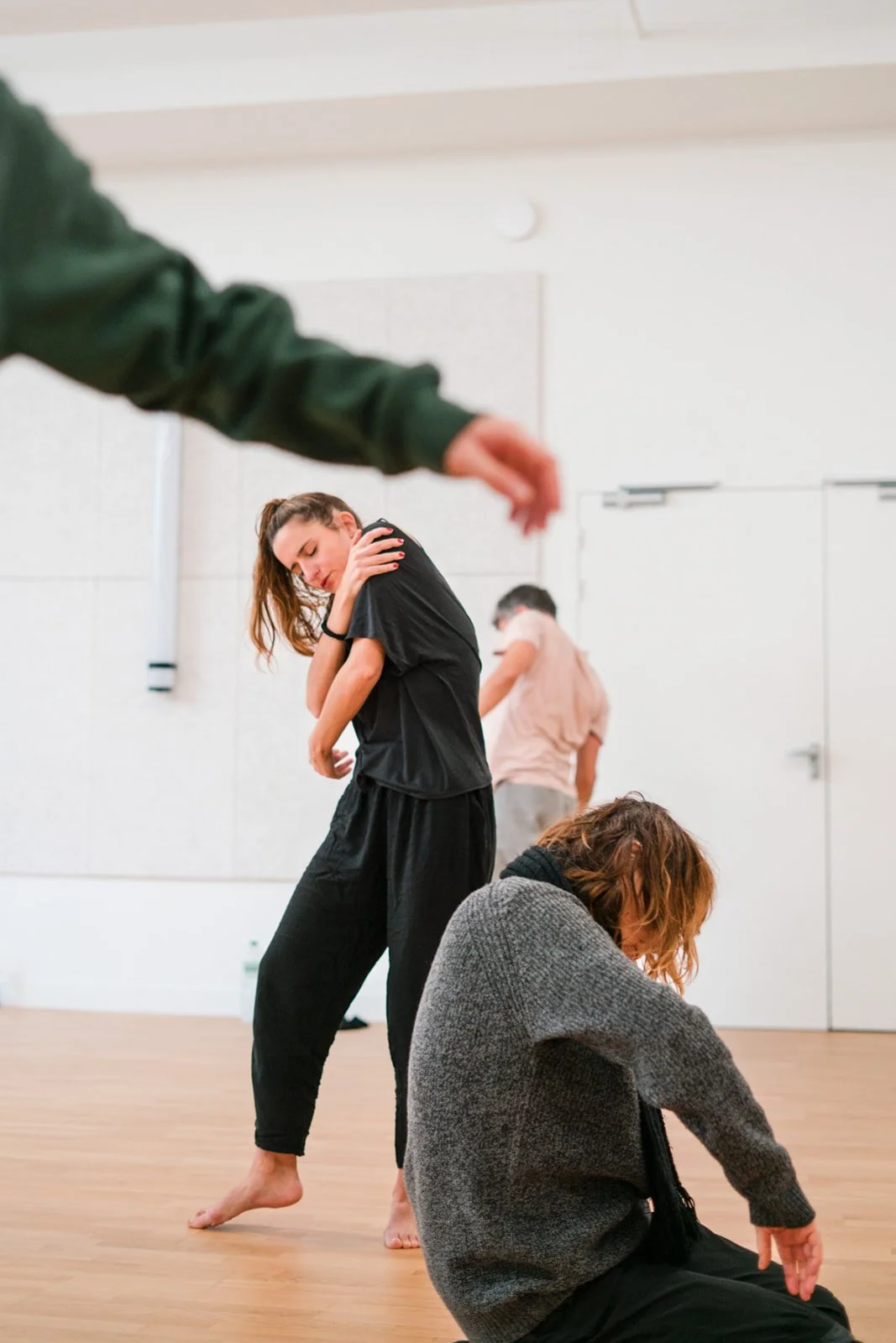Quatre personnes dans une pièce blanche semblent en pleine expression artistique ou danse, avec deux debout et deux assises, dans une ambiance calme et concentrée, lors des dimanches Life Art Process® de Stéphane Vernier.