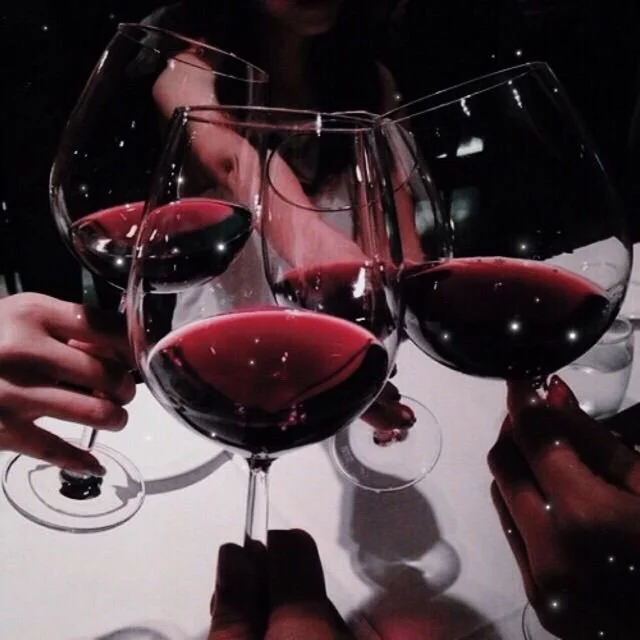 Calici di vino rosso sollevati durante un brindisi in una cena.