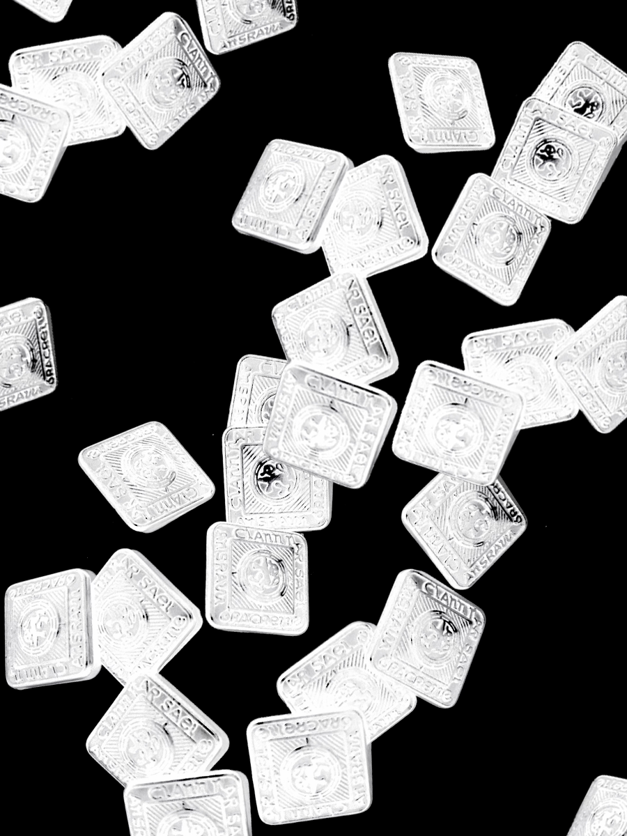 A scattered collection of small, white, square candies with the word 'CANADA' and a maple leaf design on them, set against a black background.