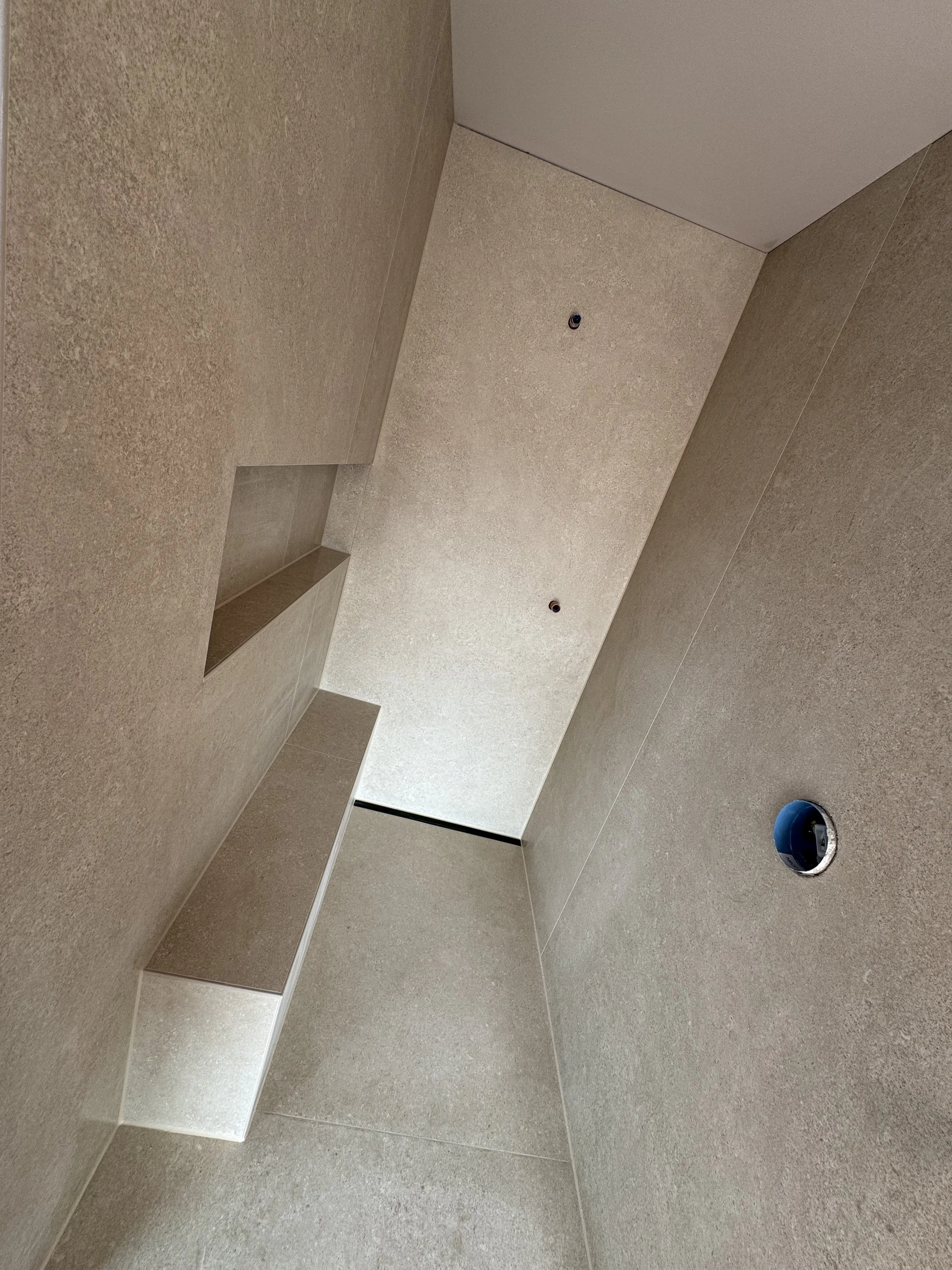 Innenraum mit beige Wänden und Decke, die Installation für Licht oder Elektrik ist noch nicht vollständig, mit zwei runden schwarzen Öffnungen in der Decke und einer blauen Abdeckung in der Wand.