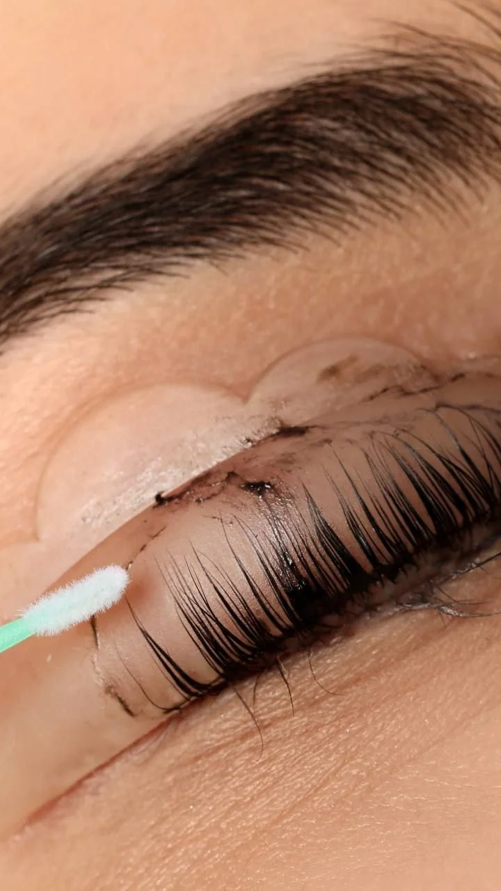 Lash tinting treatment in progress with applicator, darkening natural lashes for fuller, defined look without mascara