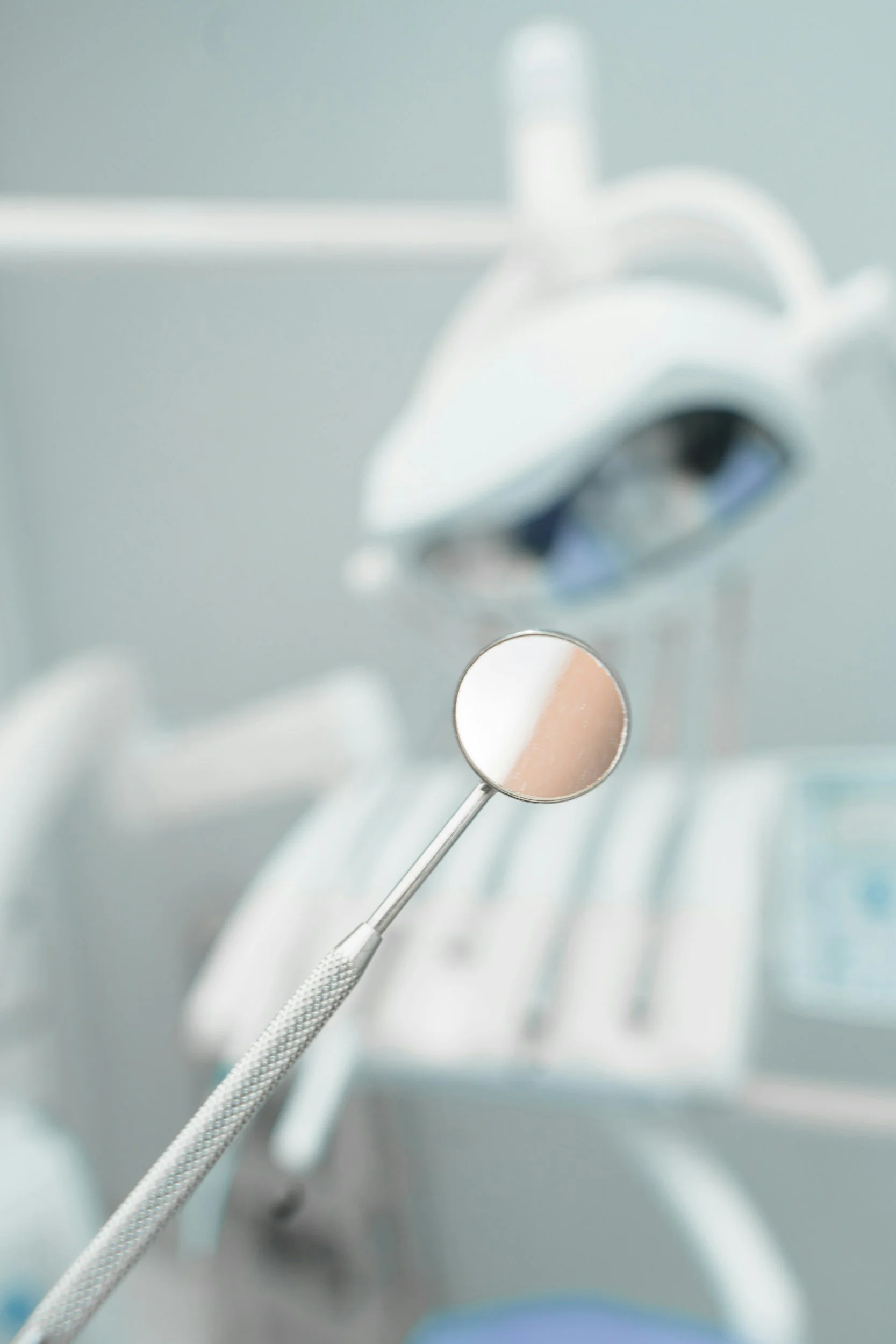 Close-up of dental tools, including a dental mirror and a dental scaler, arranged on a dental tray.