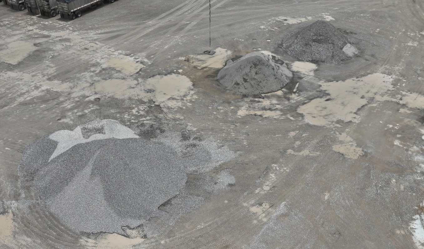 Construction site with piles of gravel and sand on a dirt ground.