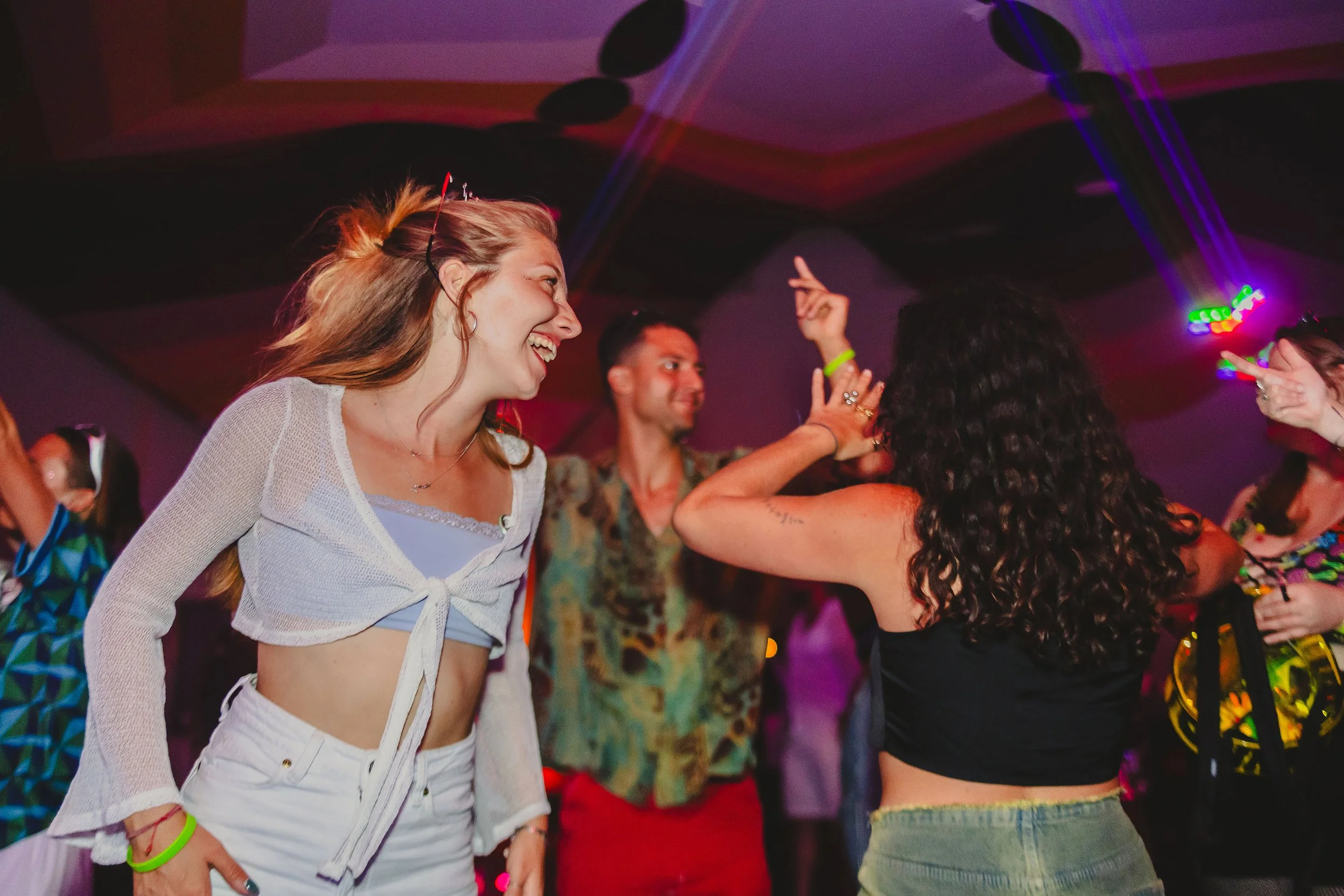 People dancing and having fun at a party or nightclub with colorful lighting.