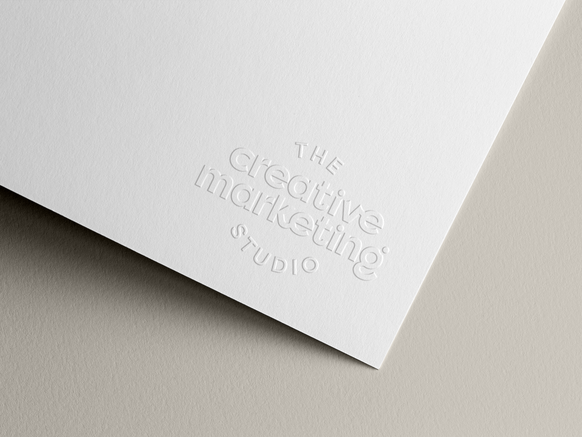 Close-up of white textured paper with embossed text reading 'The Creative Studio' and 'SG'