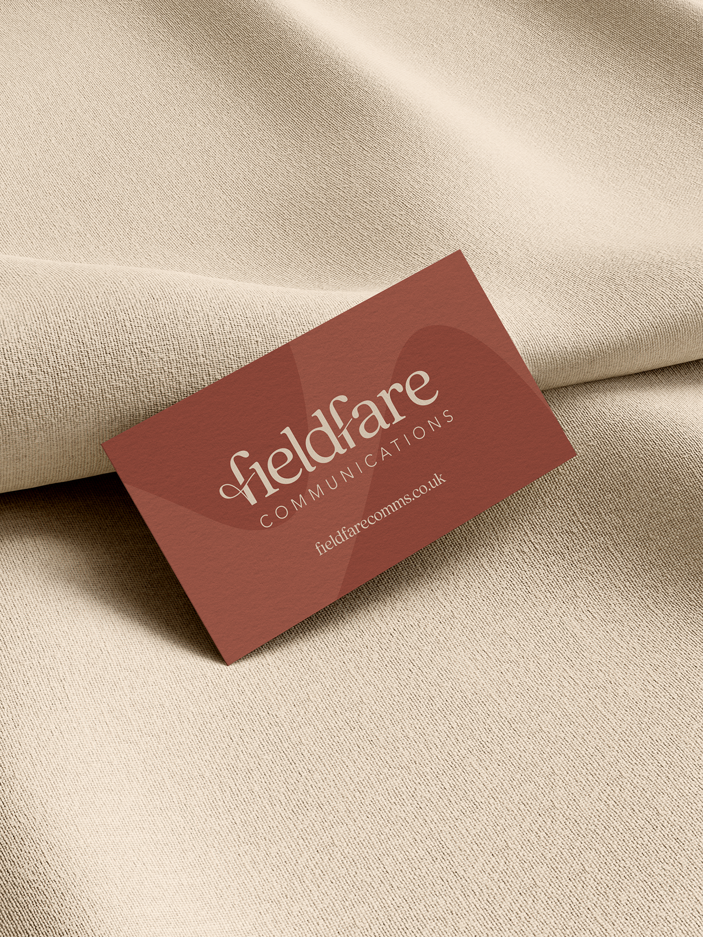 Close-up of a business card for Geldare Communications resting on beige fabric.