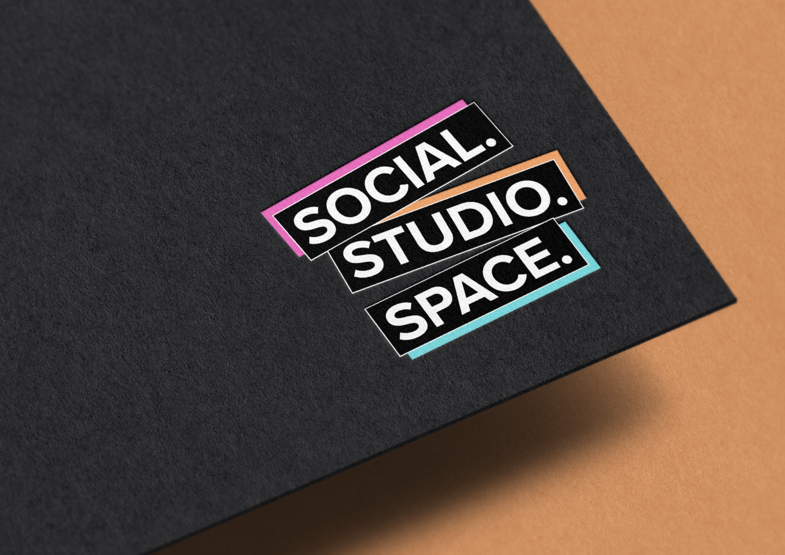 Close-up of a colorful logo design with the words 'SOCIAL. STUDIO. SPACE.' on a black surface.
