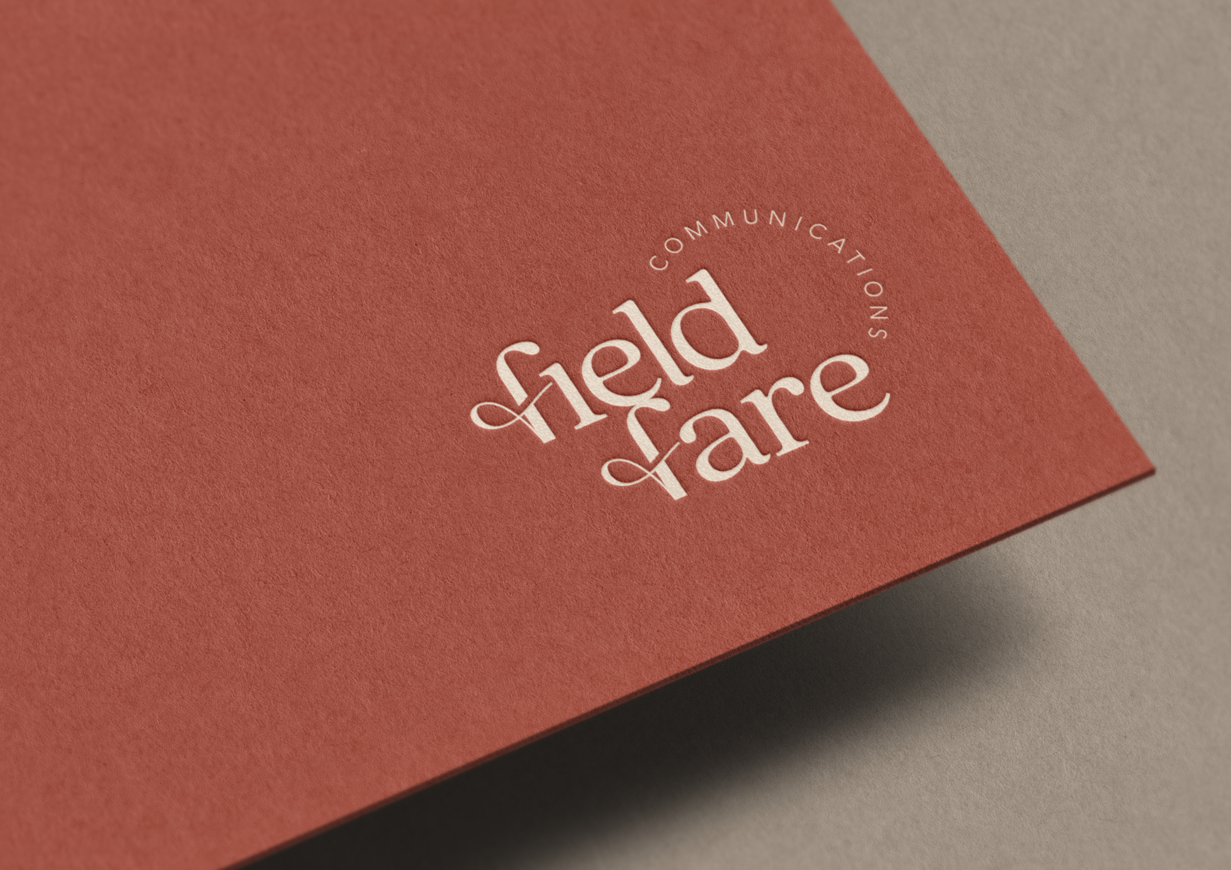 Close-up of a red textured card with white embossed business logo that reads "Fieldfare" and the text "Communication" curved around the top.