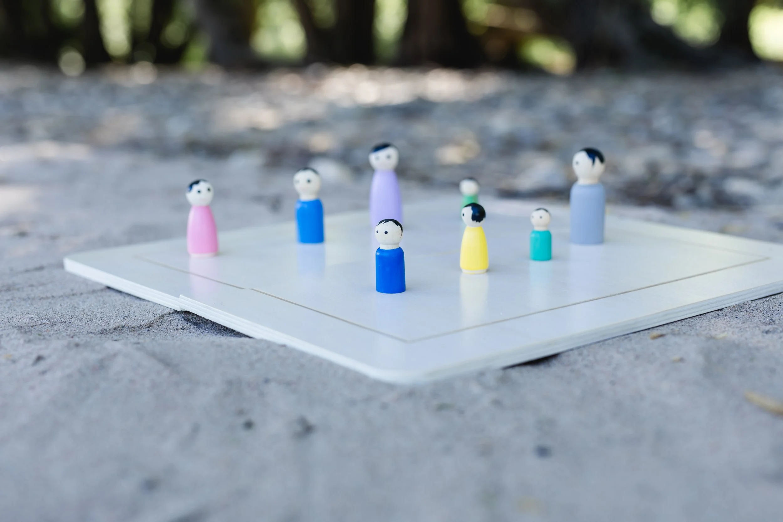 Systemische Aufstellung und psychologisches Verhaltenscoaching in Tönisvorst. Kleine bunte Figuren stehen auf einem Spielfeld im Freien.