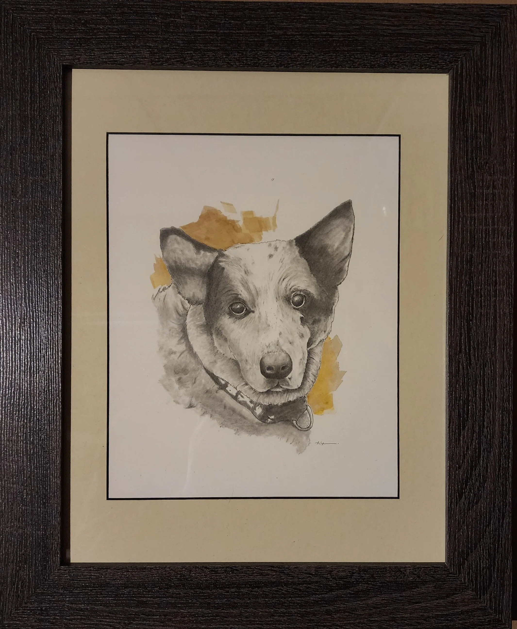 Framed watercolor painting of a dog looking forward, with a brown and yellow background behind the dog.