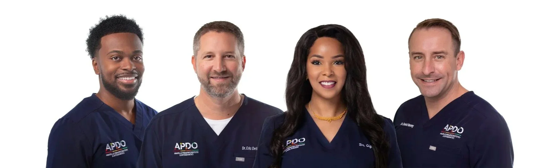 Team headshot of four dentists in Amarillo, Tx wearing navy scrubs with APDO logo standing against a white background, smiling at the camera.
