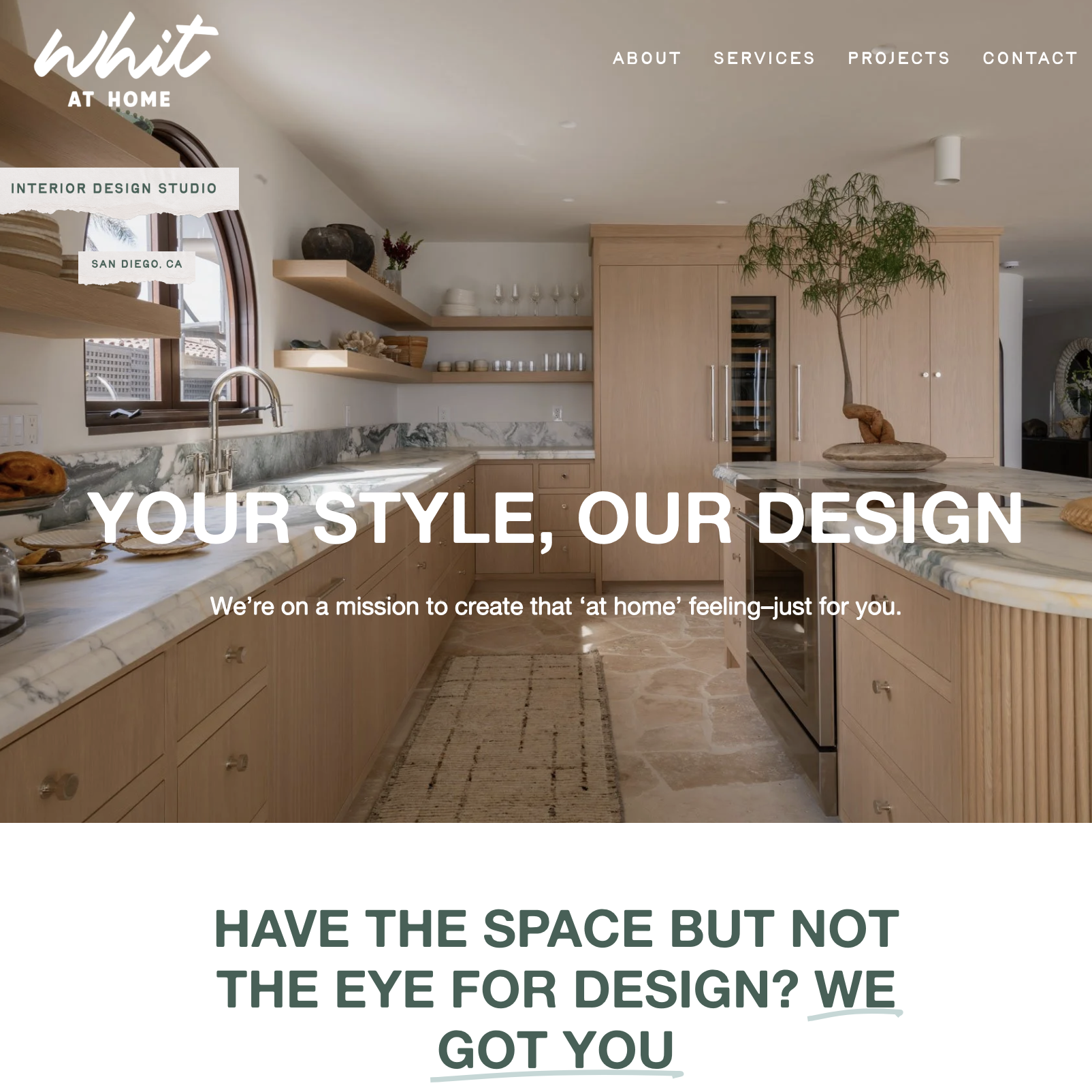 Interior view of a modern kitchen with wooden cabinets, marble countertops, an arched window, and a potted plant on an island. The website offers interior design services in San Diego, CA.