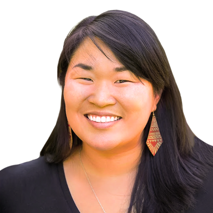 A smiling Asian woman with long black hair wearing a black top and earrings.