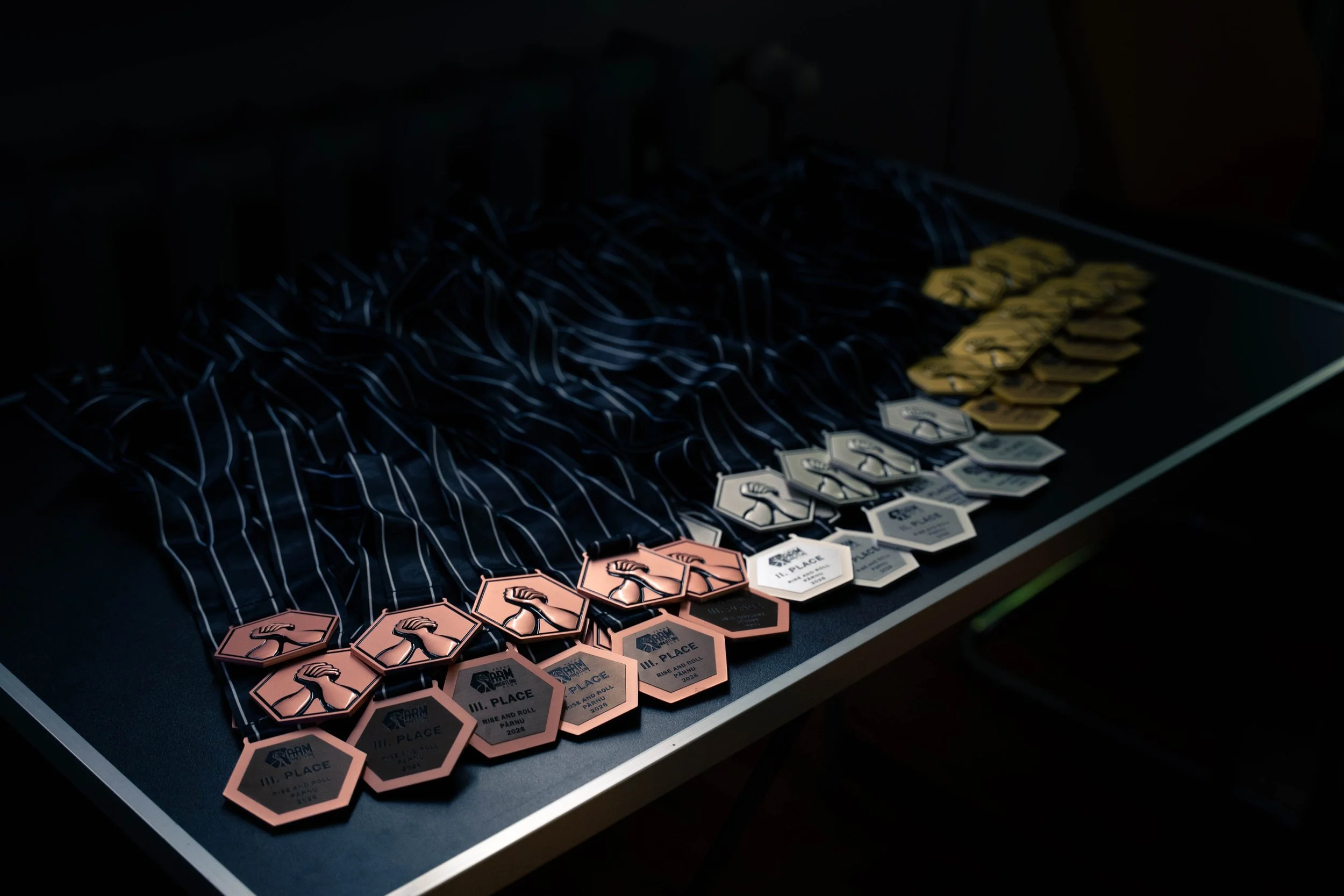 Medals with ribbons arranged on a table, with medals of pink, white, and yellow colors.