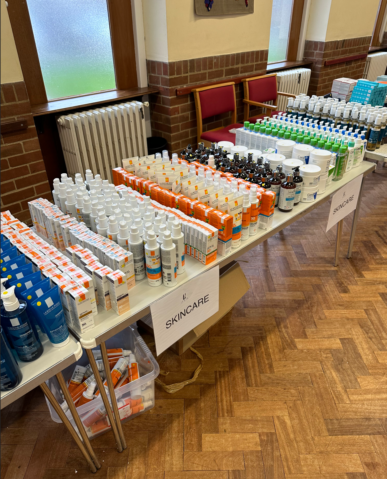Table filled with skincare products such as lotions, sprays, and creams, organized in rows with signs labeled 'SKINCARE'.