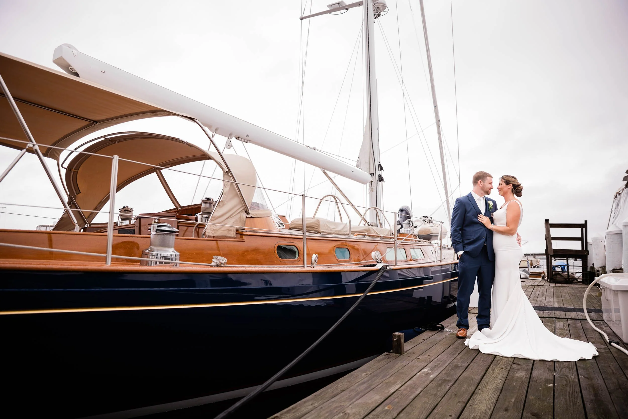A bride and groom beside a sailboat on the dock at Regatta Place on Goat Island