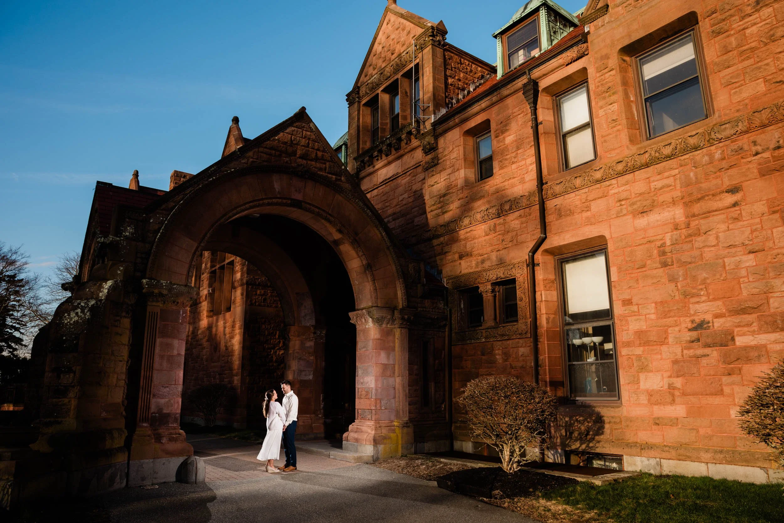 An engaged couple posing in front of Vinland Estate in Newport