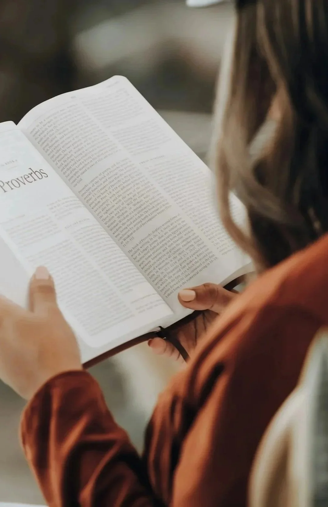 Person reading a book titled 'Proverbs'.