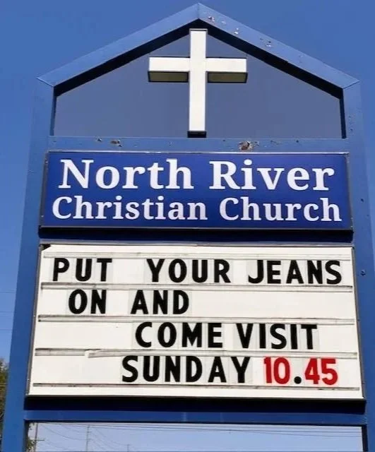Sign for North River Christian Church with a message about putting on jeans and visiting on Sunday at 10:45.