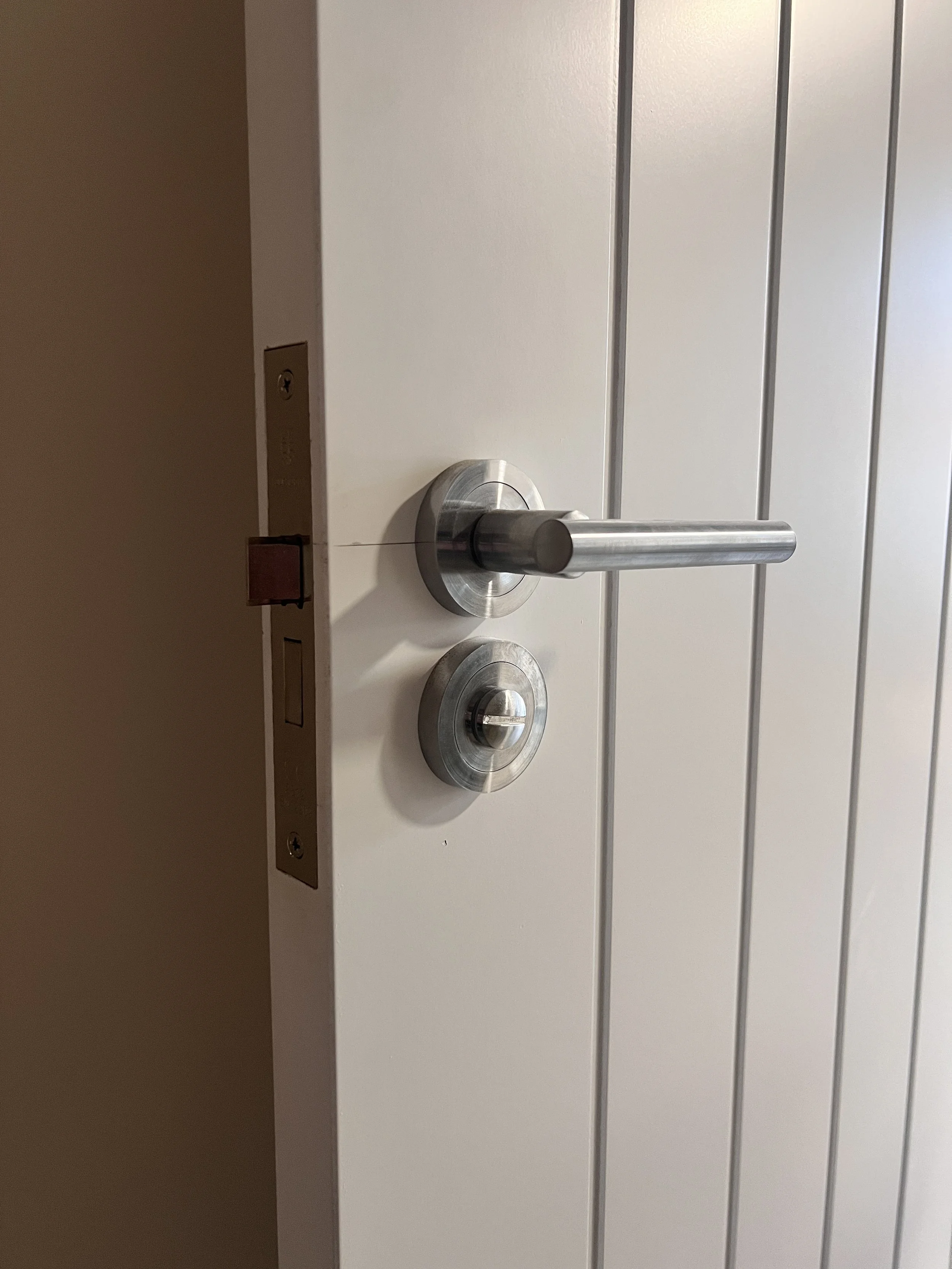 Close-up of a silver door handle and lock on a white paneled door.