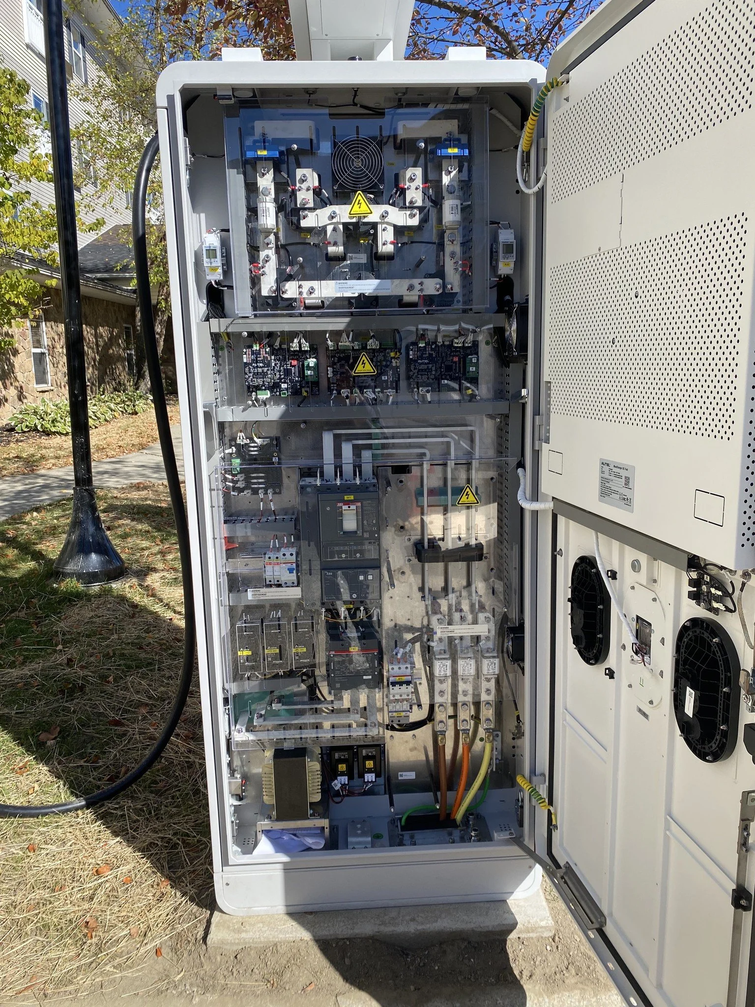 Open electrical or control cabinet with various electronic components, circuit boards, wiring, and cooling fans visible inside.
