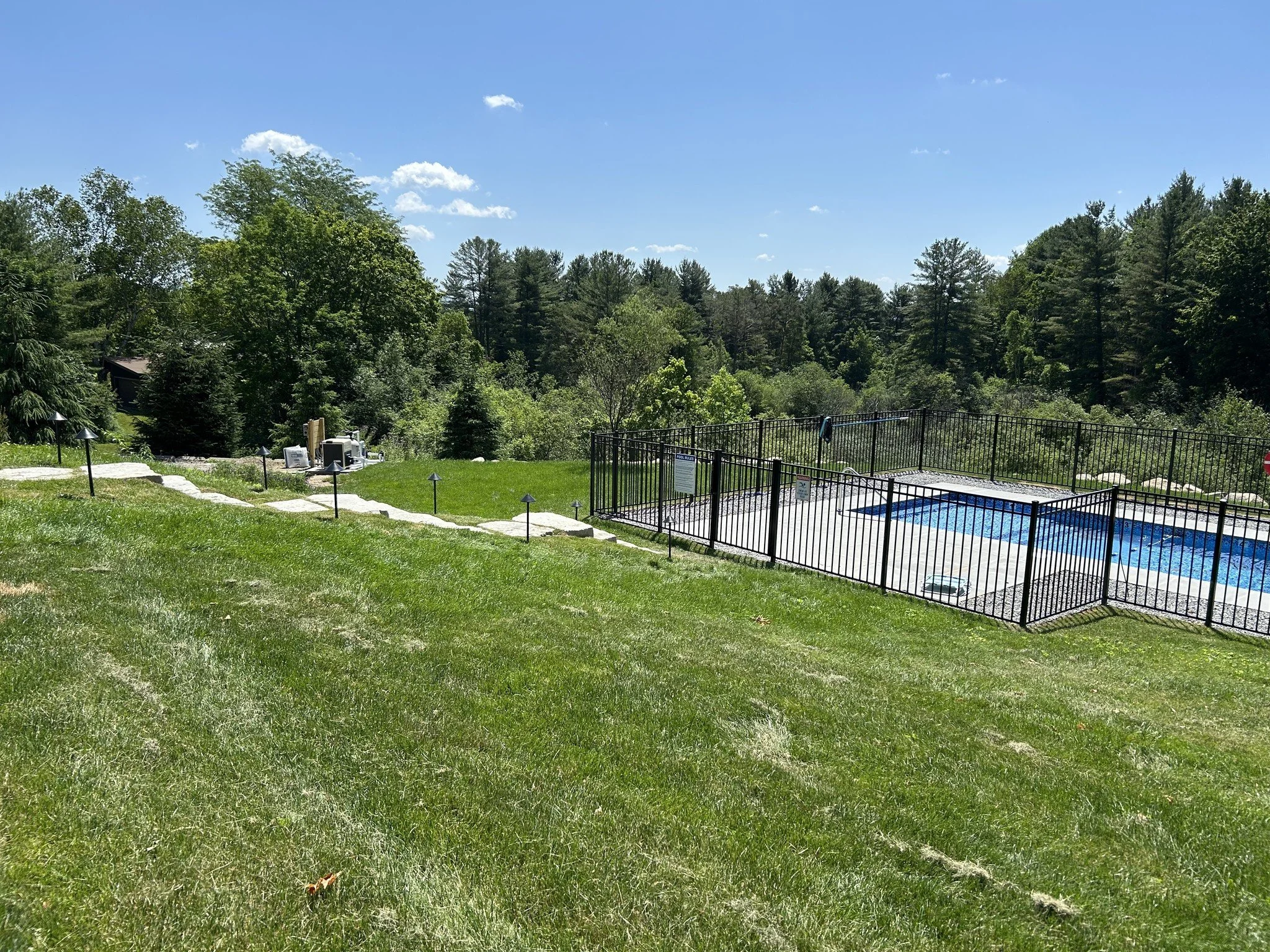 A freshly wired outdoor swimming pool in the Berkshires with landscape lighting surrounding it.