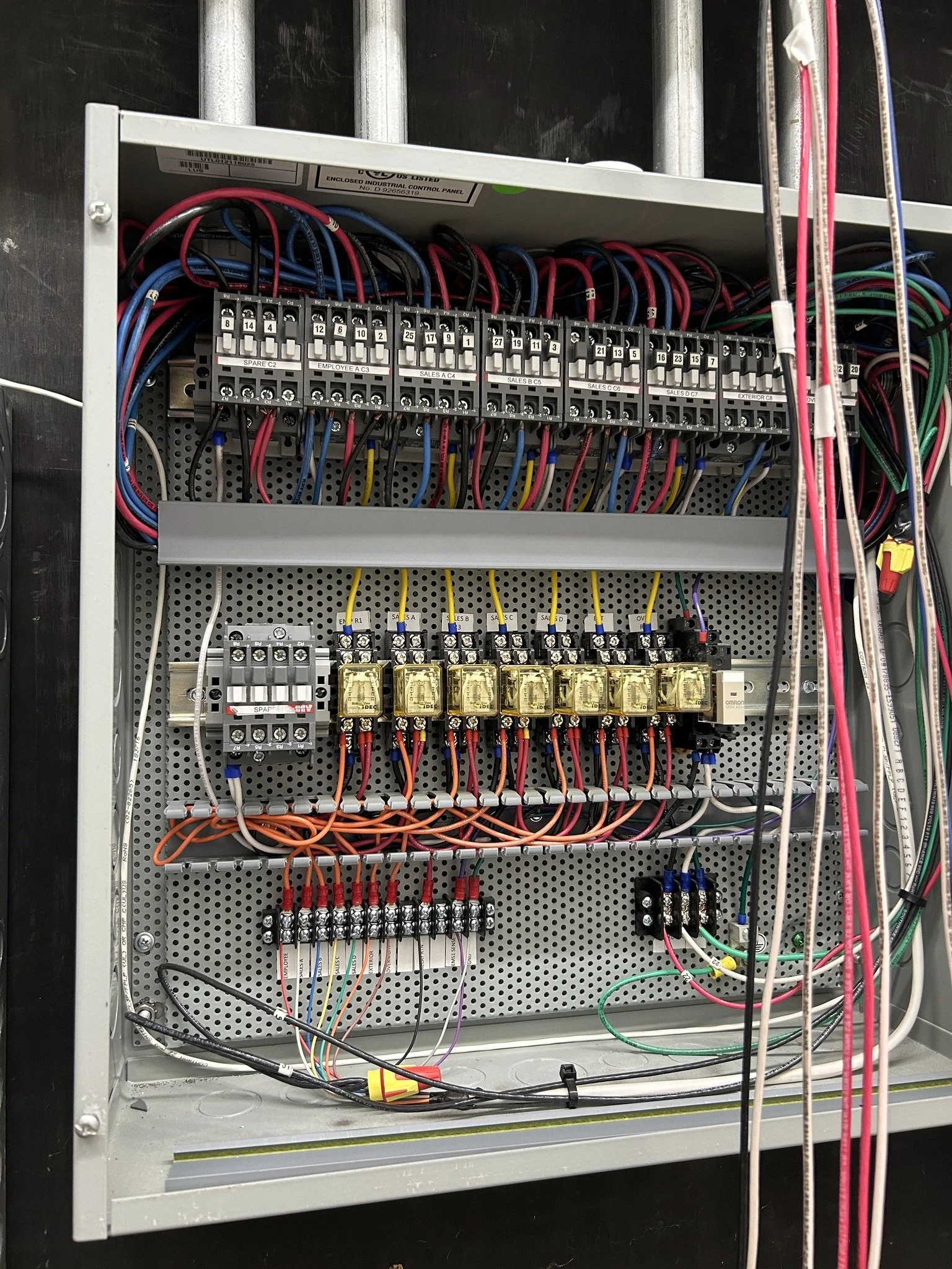 An electrical control panel with multiple wires, relays, and circuit breakers organized inside a metal box.