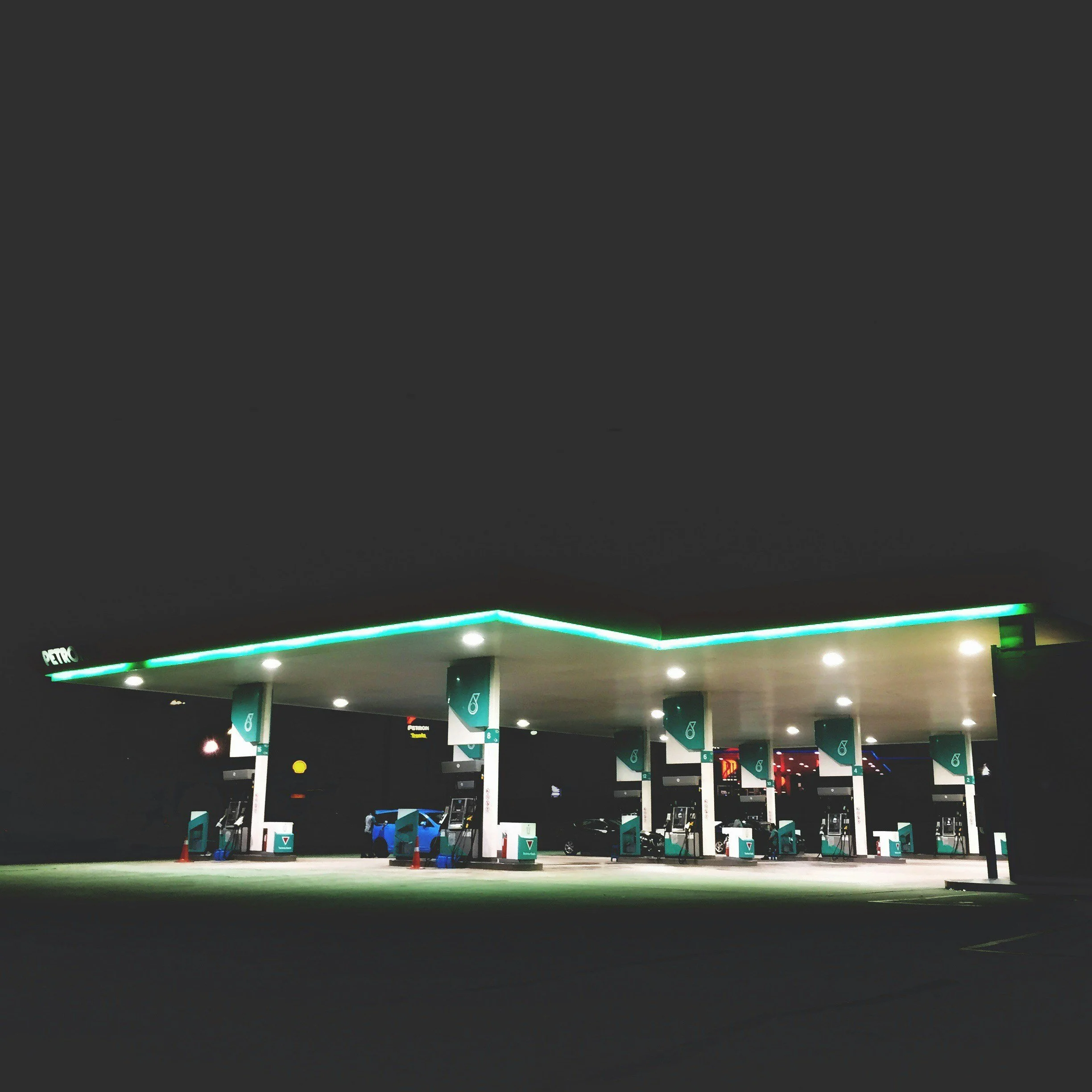 Lone electric vehicle charging station at night with multiple chargers and minimal activity.