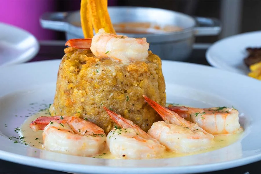 Shrimp and corn pudding on a white plate with sauce and garnishes