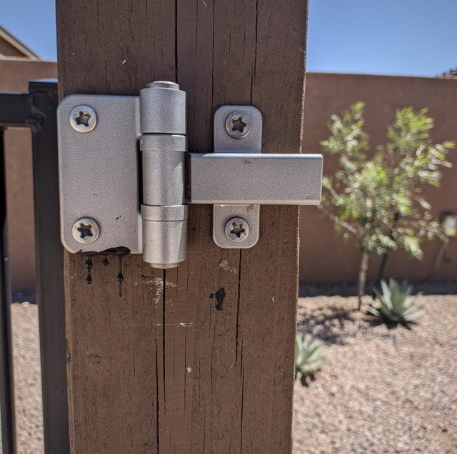 worn gate hinge pin dragging against paver below