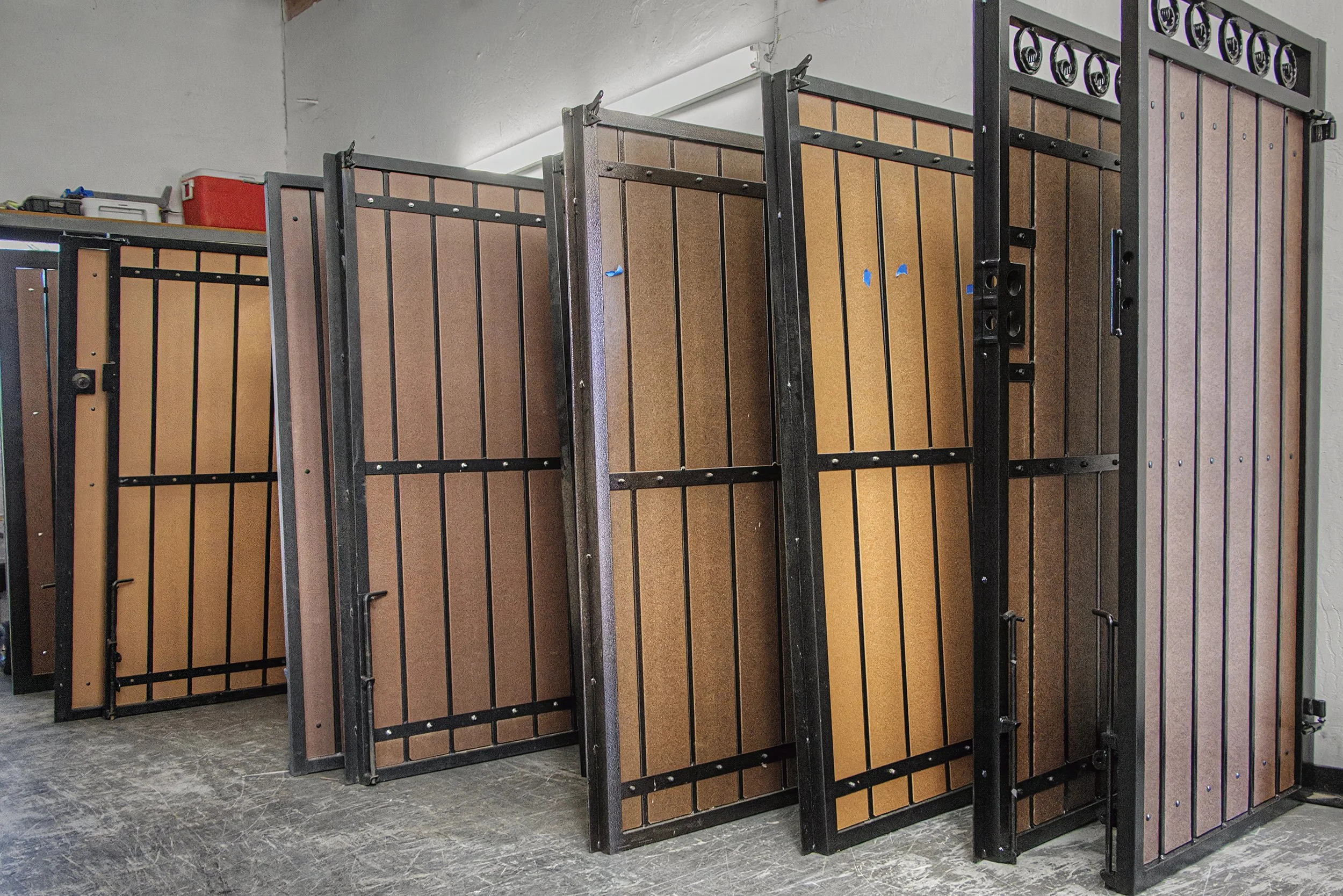 A row of brown and black lockers, some with blue tape marks, in a storage or changing room with a gray tiled floor and white ceiling.
