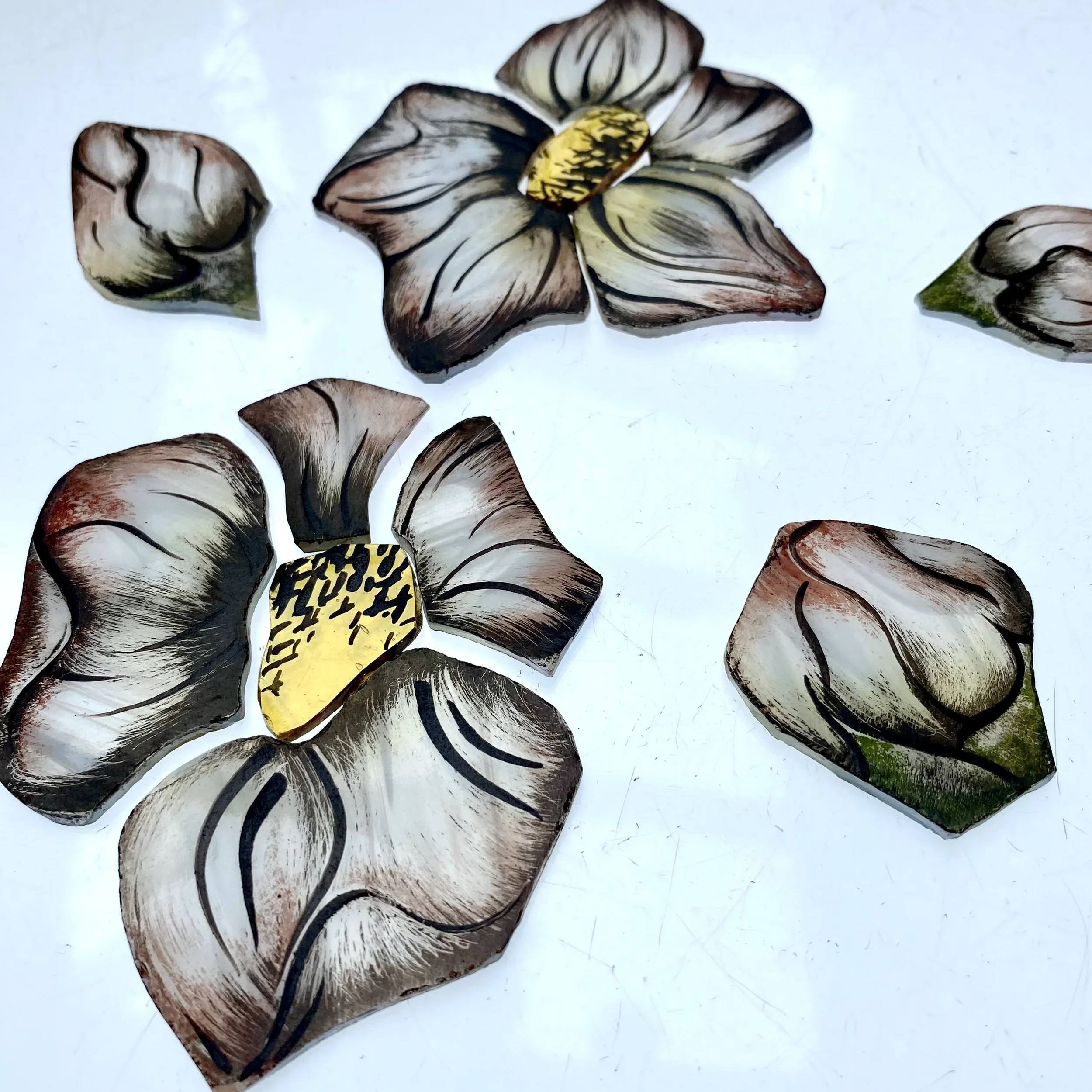 Handmade wooden flower with dark and light wood grains and yellow center, laid on white background.