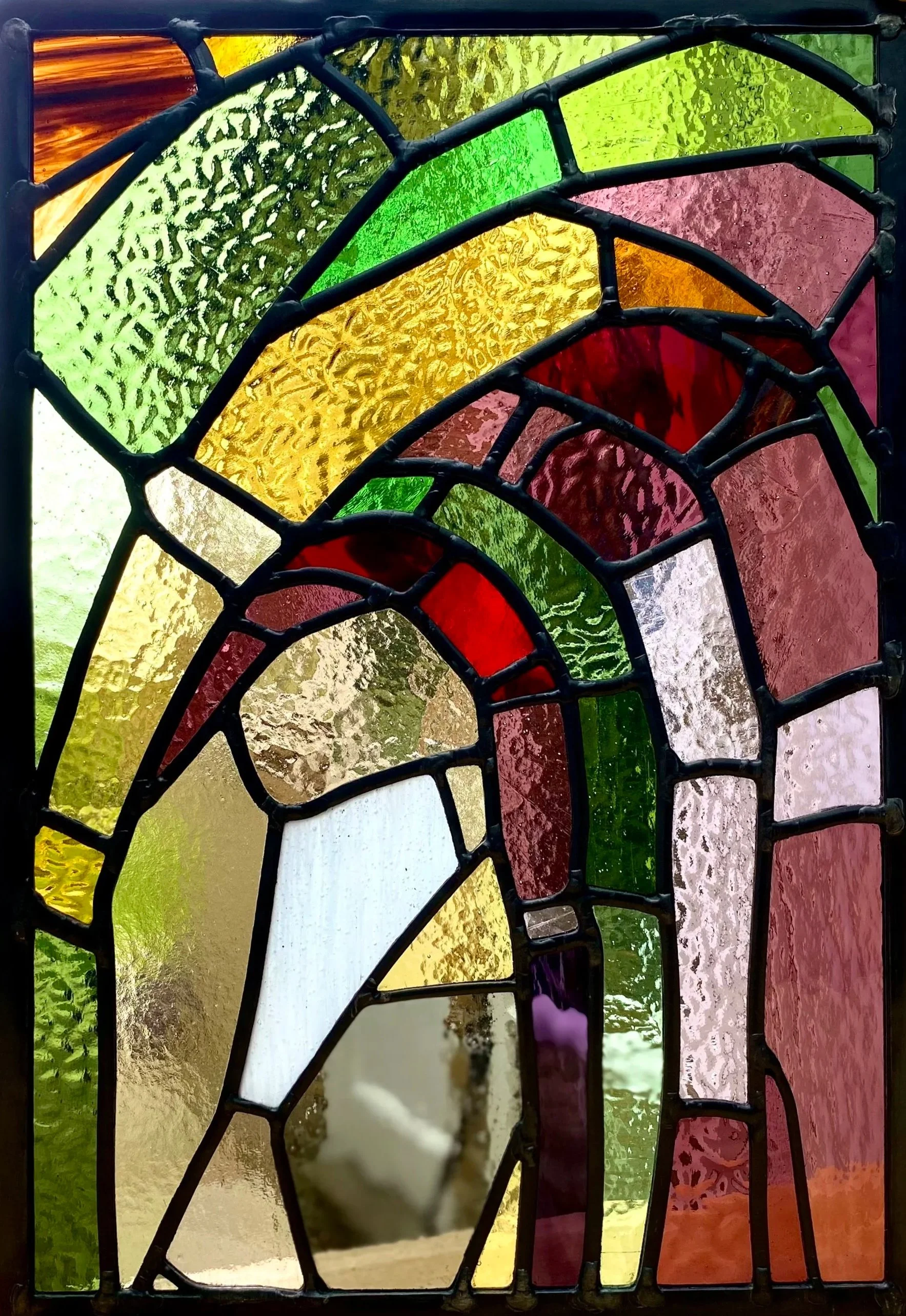 Colorful stained glass window with abstract design, featuring various textured and colored glass pieces.