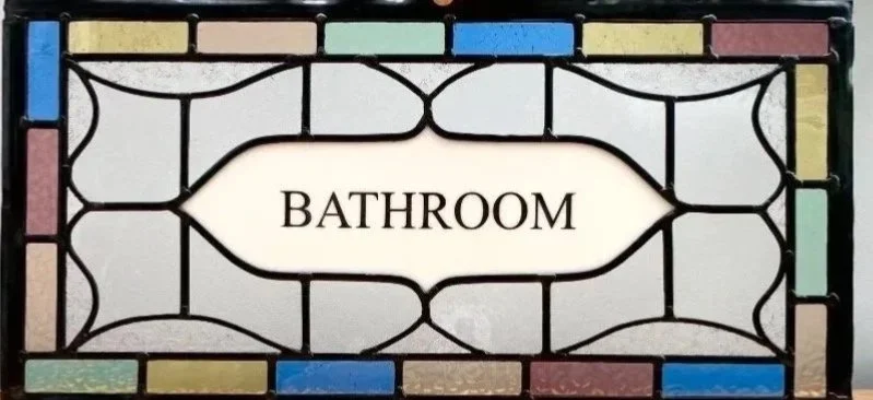 Decorative stained glass sign with the word 'BATHROOM' in the center.  Traditional stained glass panel by stained glass artist zoe henderson in south east london highly recommended talented glass panel maker