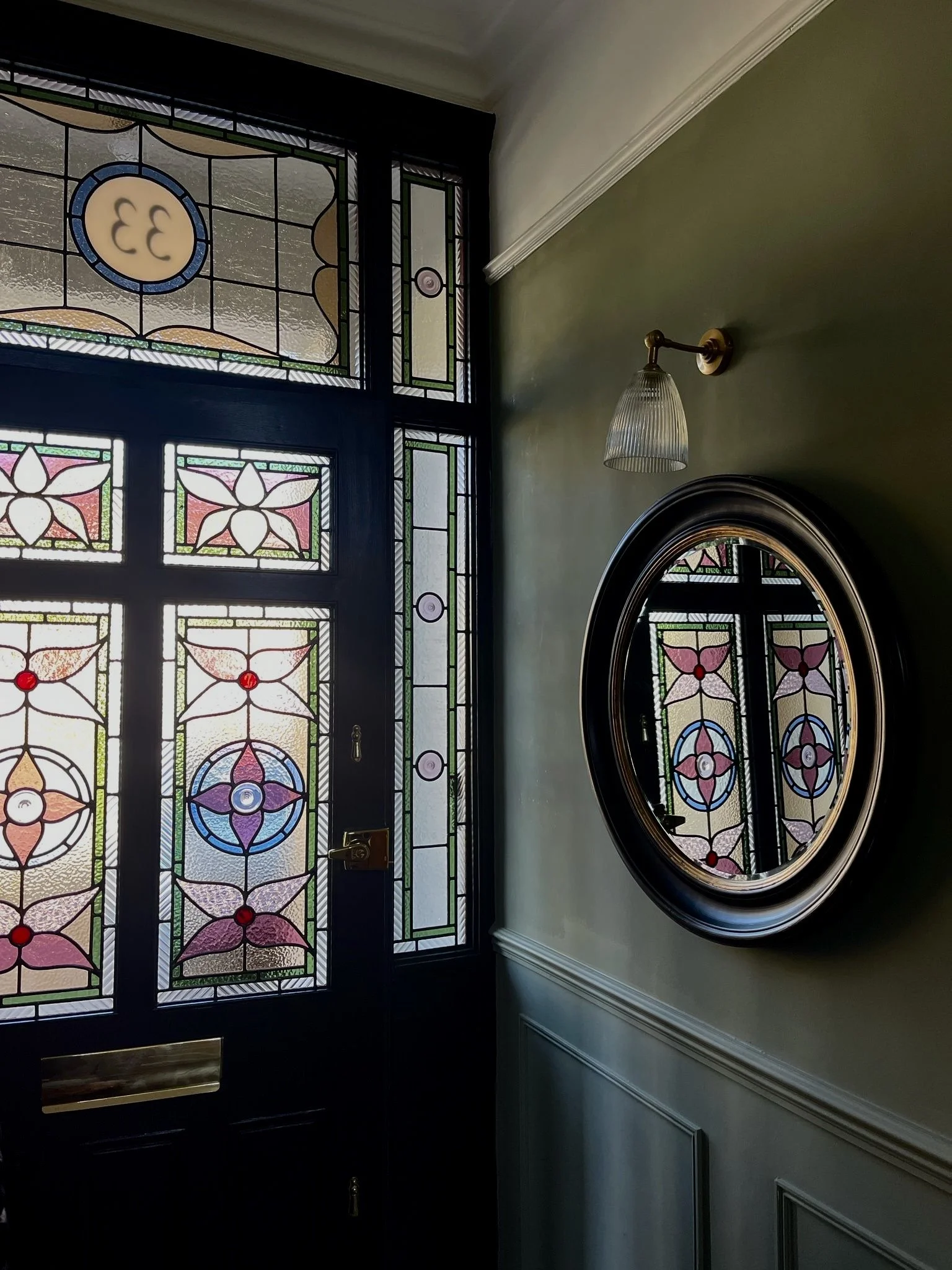 Interior view of a doorway with stained glass panels featuring house number.  Zoe Henderson