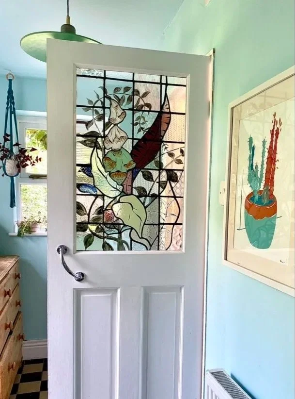 Interior view of a room with a stained glass door featuring foxgloves and leaves.  Interior hand painted leaded panel for a bathroom by zoe henderson stained glass designer and maker in south east london top rated.