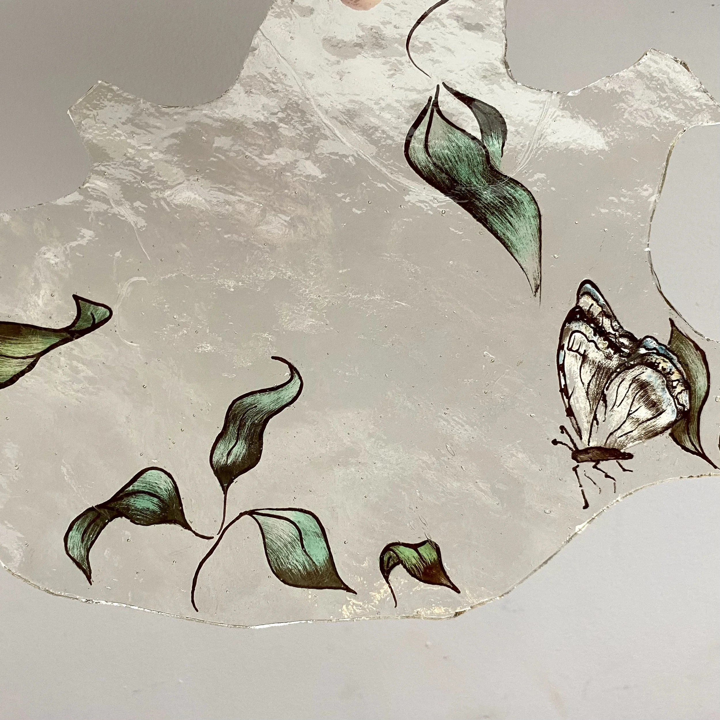 Close-up of torn wallpaper with a butterfly and leaf design, showing peeling edges and a textured surface.